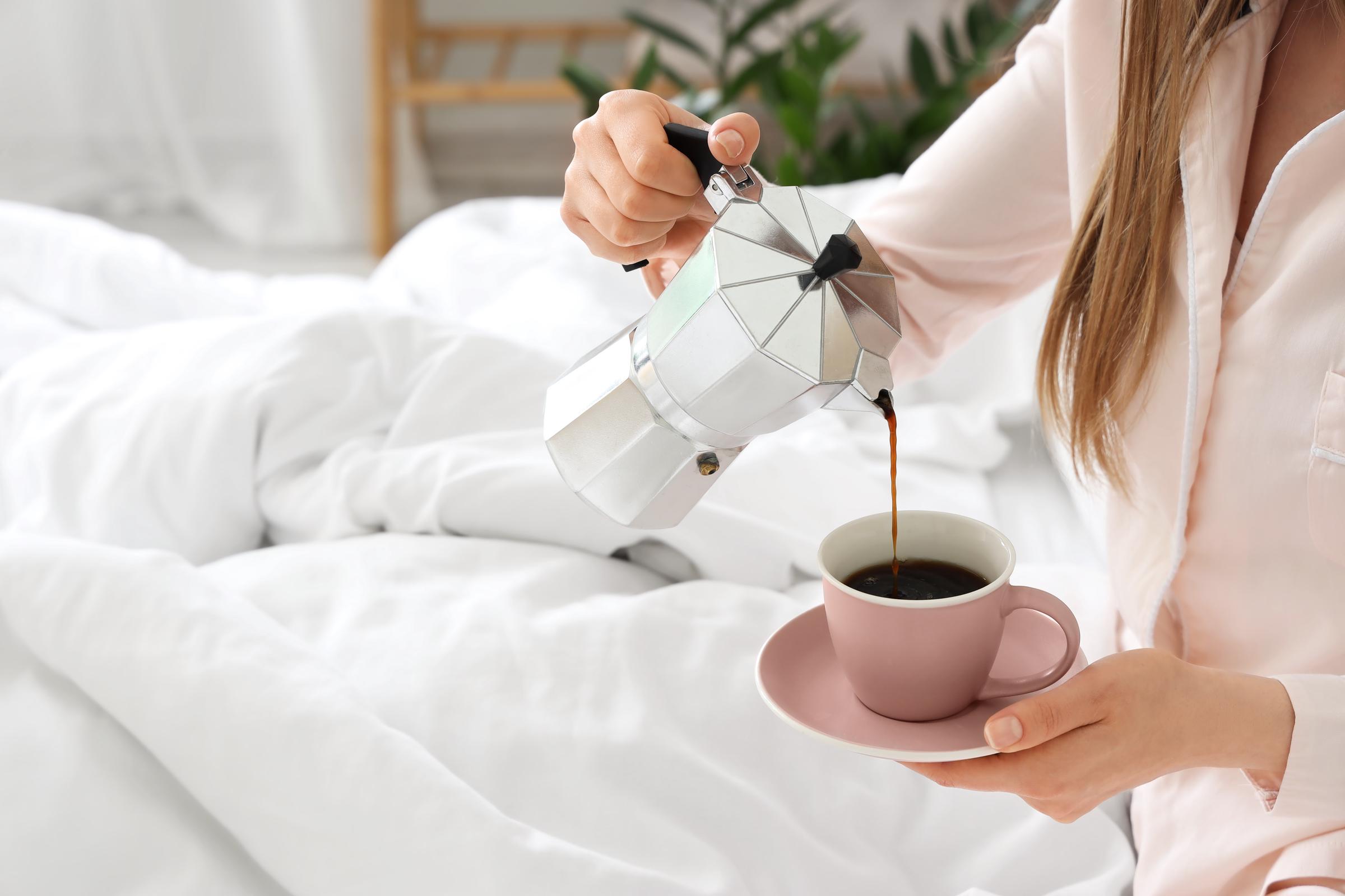 A woman pouring coffee in bed | Source: Shutterstock