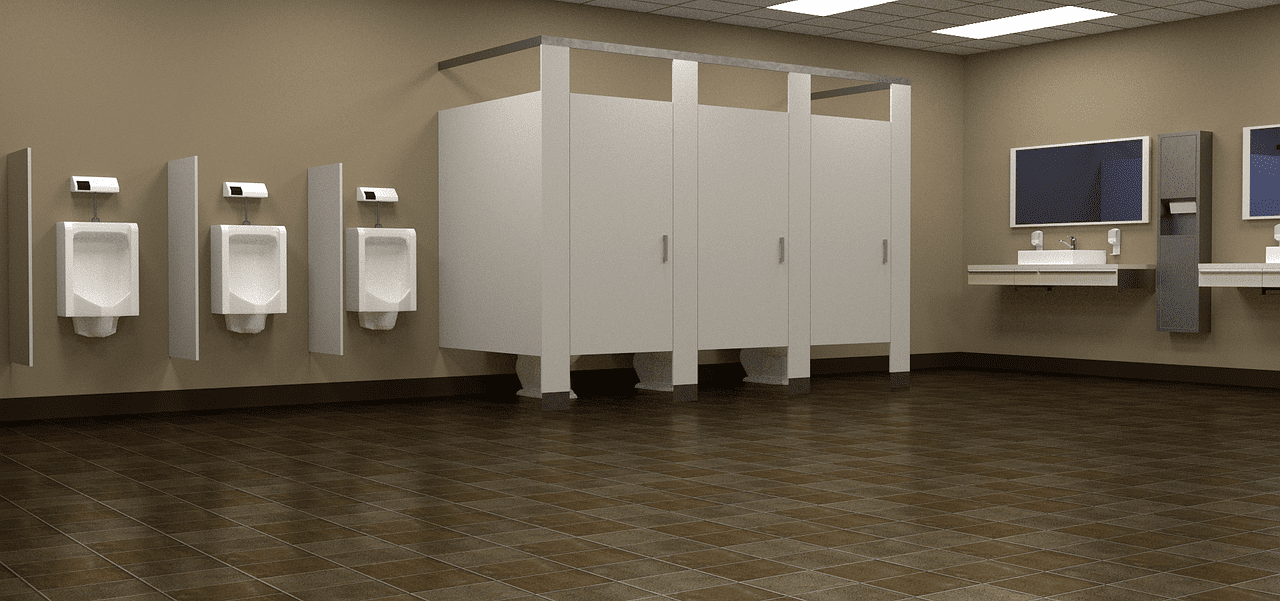 A clean bathroom with urinals and three closed toilet stalls | Photo: Pixabay/David Rinehart