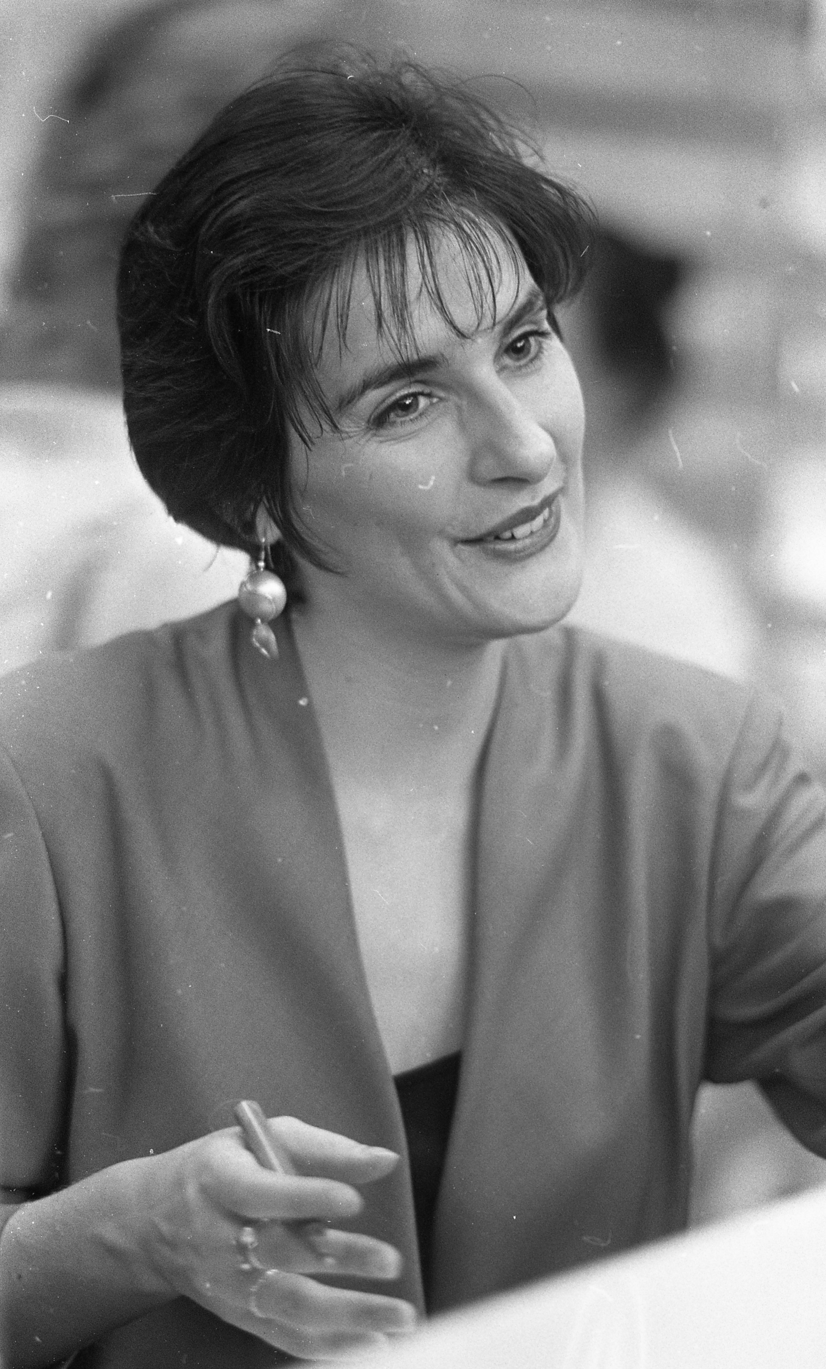 Seated at a signing table inside Virgin Megastore, Enya smiles softly as she signs autographs for waiting fans in circa October 1988, shortly after "Orinoco Flow" propelled her to international fame. The candid black-and-white moment captures the early days of her global success, when the once-unknown Irish singer was suddenly at the centre of intense public attention.