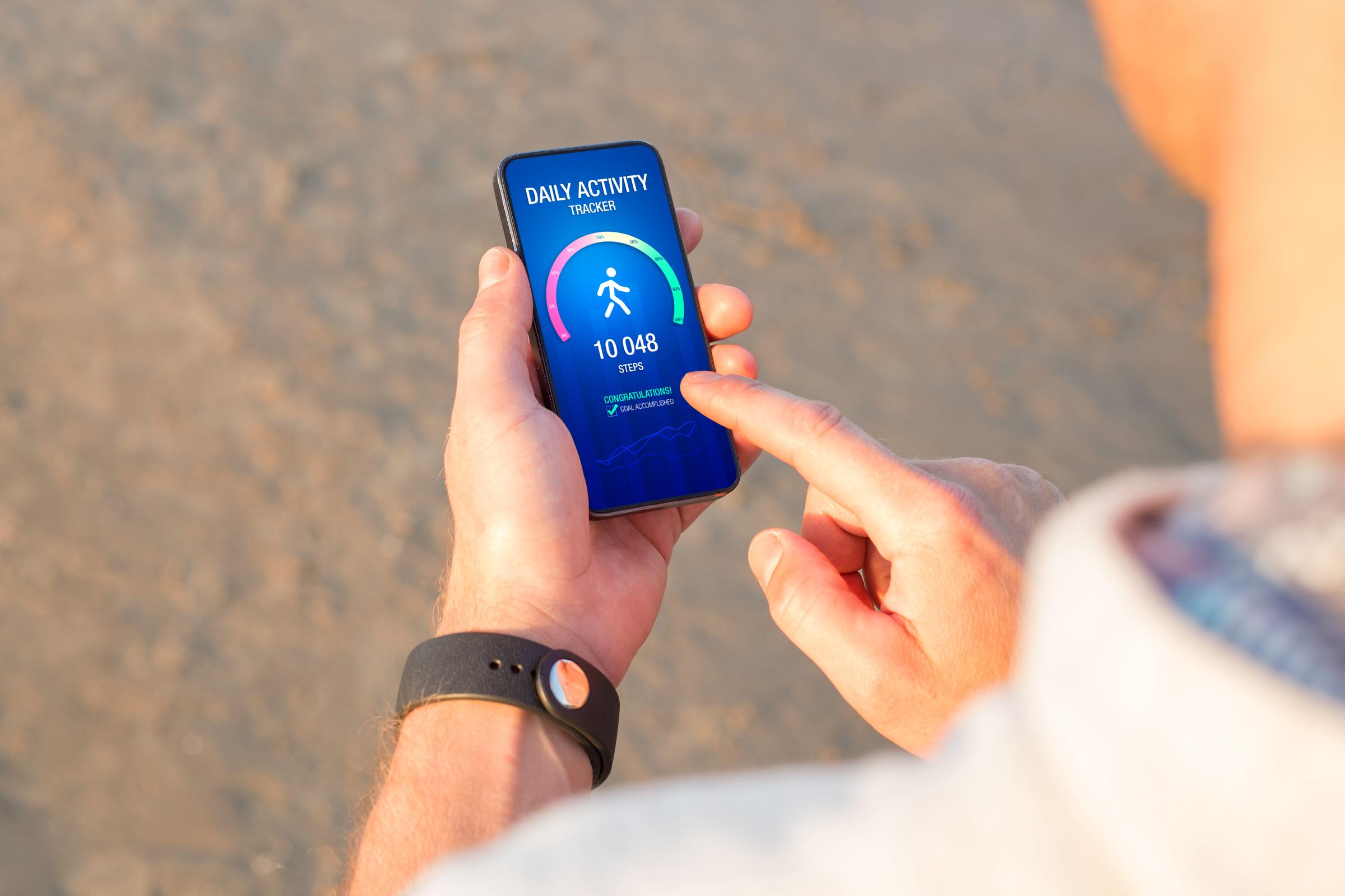A man using a daily activity tracking app on his phone, showing a 10,000 steps daily goal achievement | Source: Getty Images