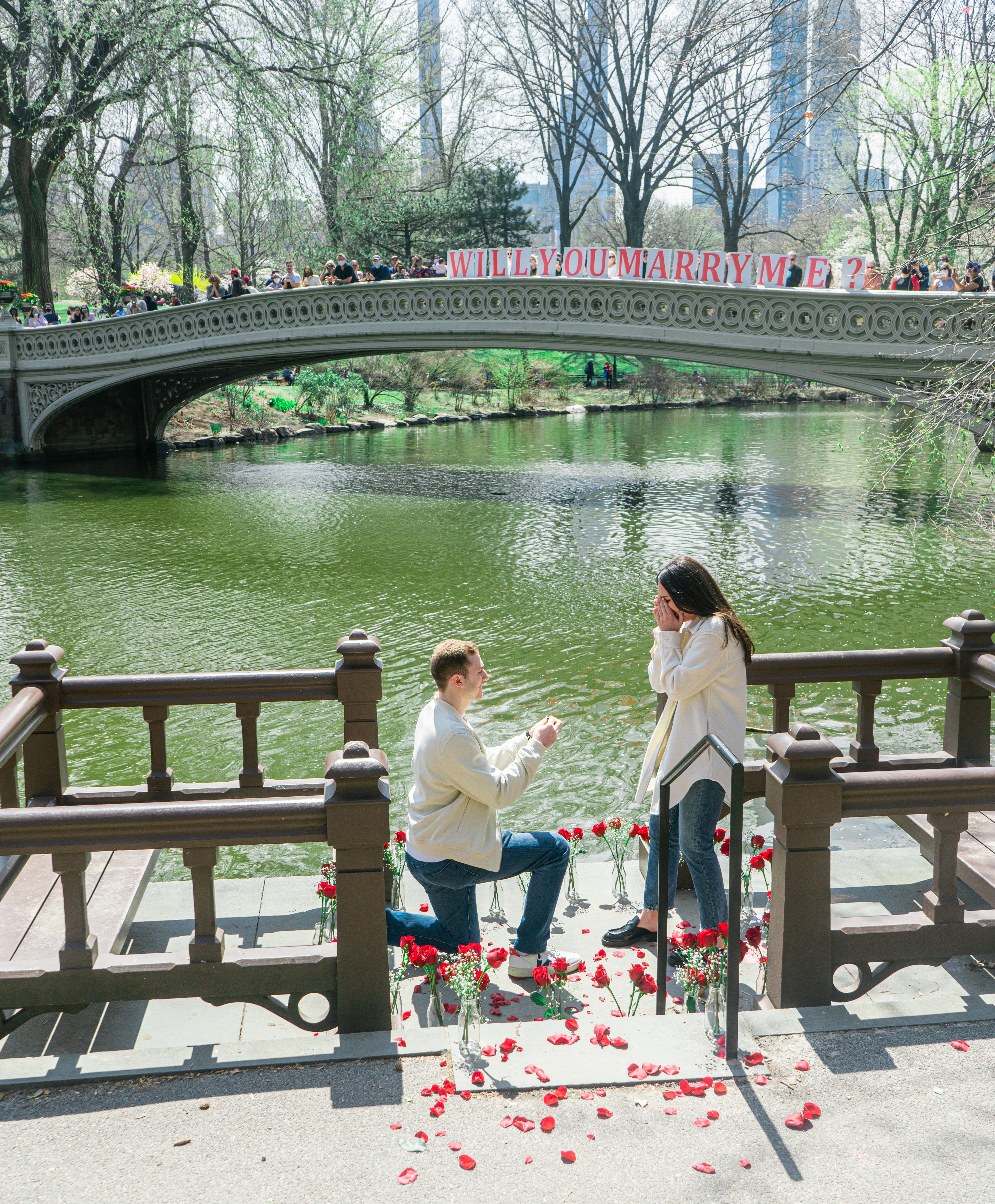 A man elaborately proposes to a woman next to a river with red roses a sign that asks her the big question | Photo: Unsplash/Dylan Sauerwein 