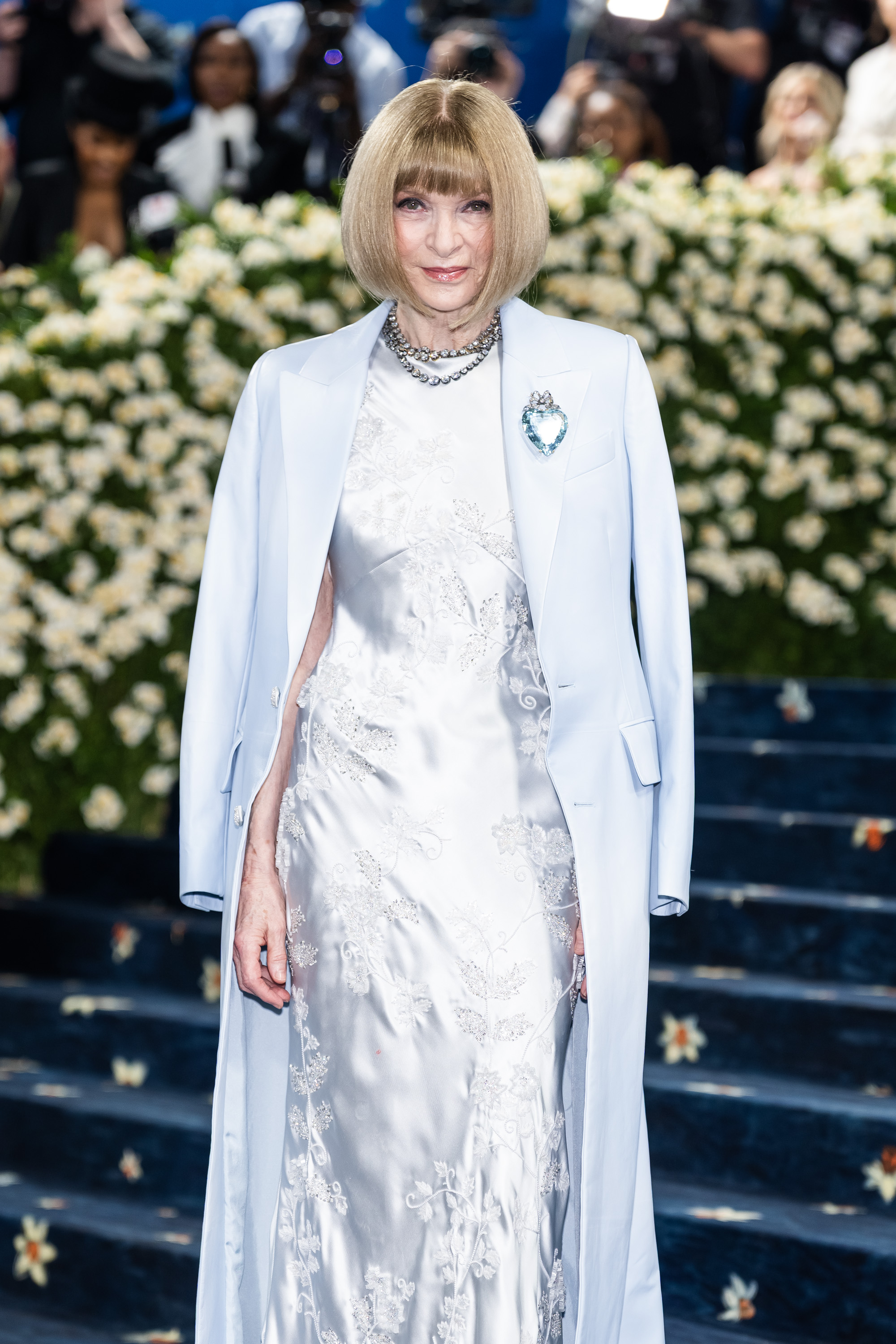 With photographers capturing every angle, Anna Wintour stands poised in her icy blue ensemble, featuring a crystal brooch and layered necklace, at the 2025 Met Gala celebrating "Superfine: Tailoring Black Style" in New York City.