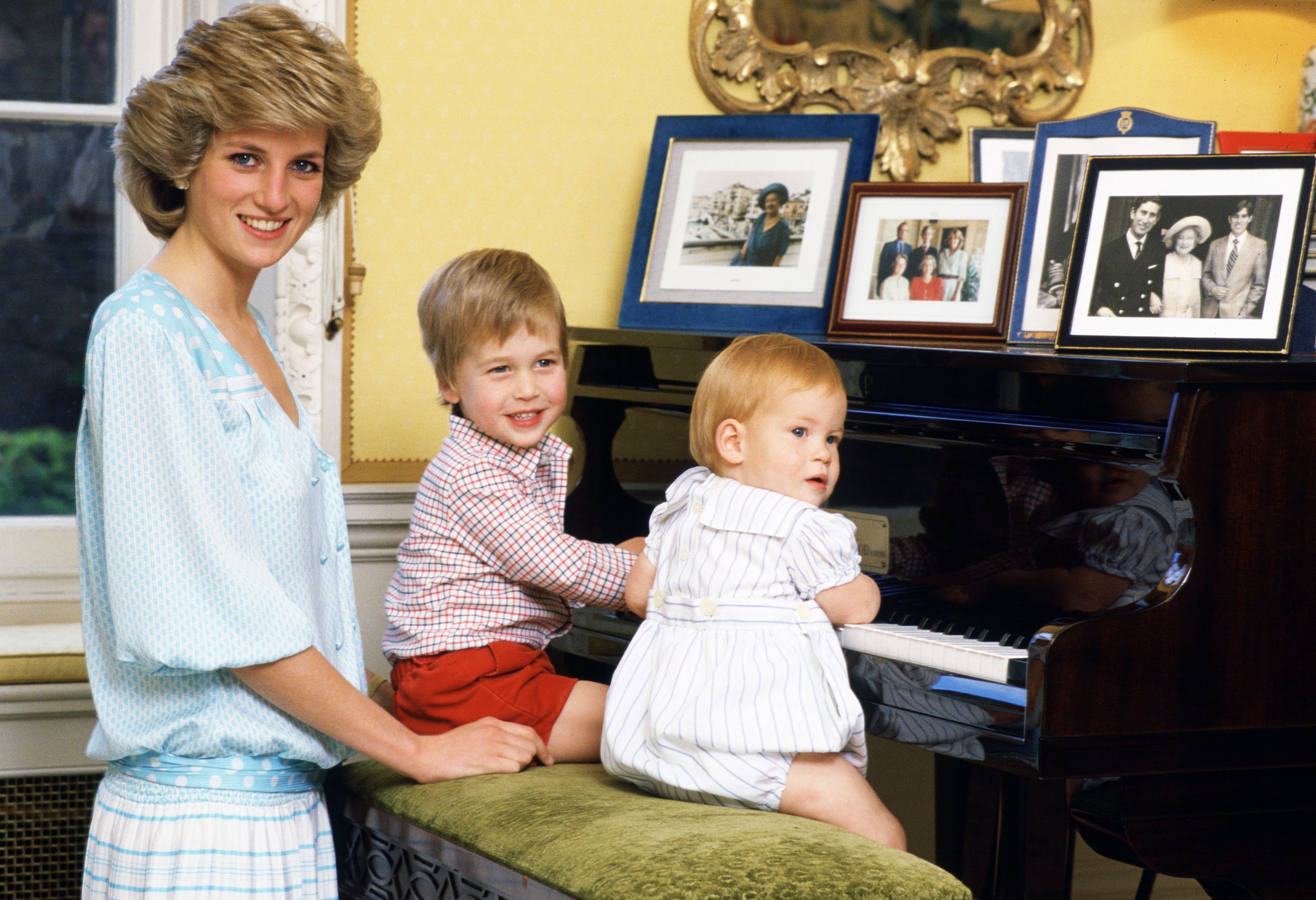 Diana, princesa de Gales, con sus hijos, el príncipe William y el príncipe Harry, tocando el piano en el palacio de Kensington. | Foto: Getty Images