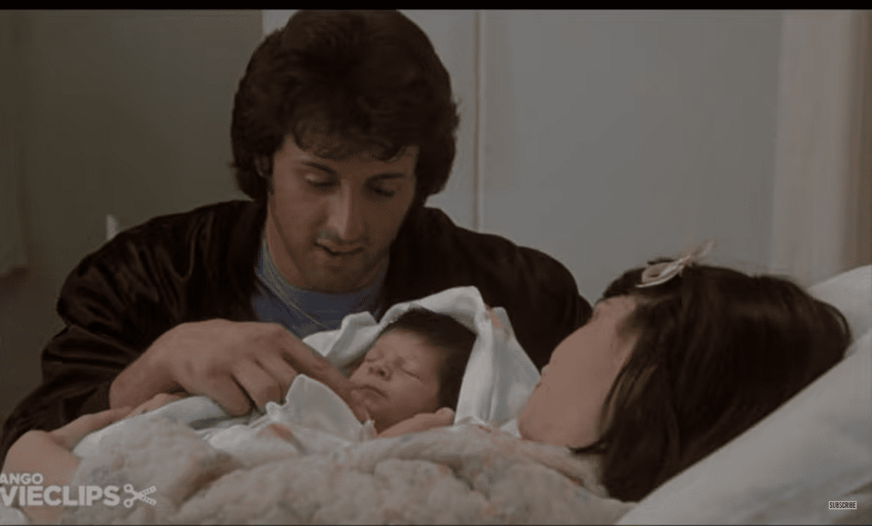 Sylvester Stallone como Rocky Balboa, Seargeoh Stallone como Robert 'Rocky' Jr. y Talia Shire como Adrian Pennino, en la película "Rocky II" ┃Foto: YouTube/@Movieclips