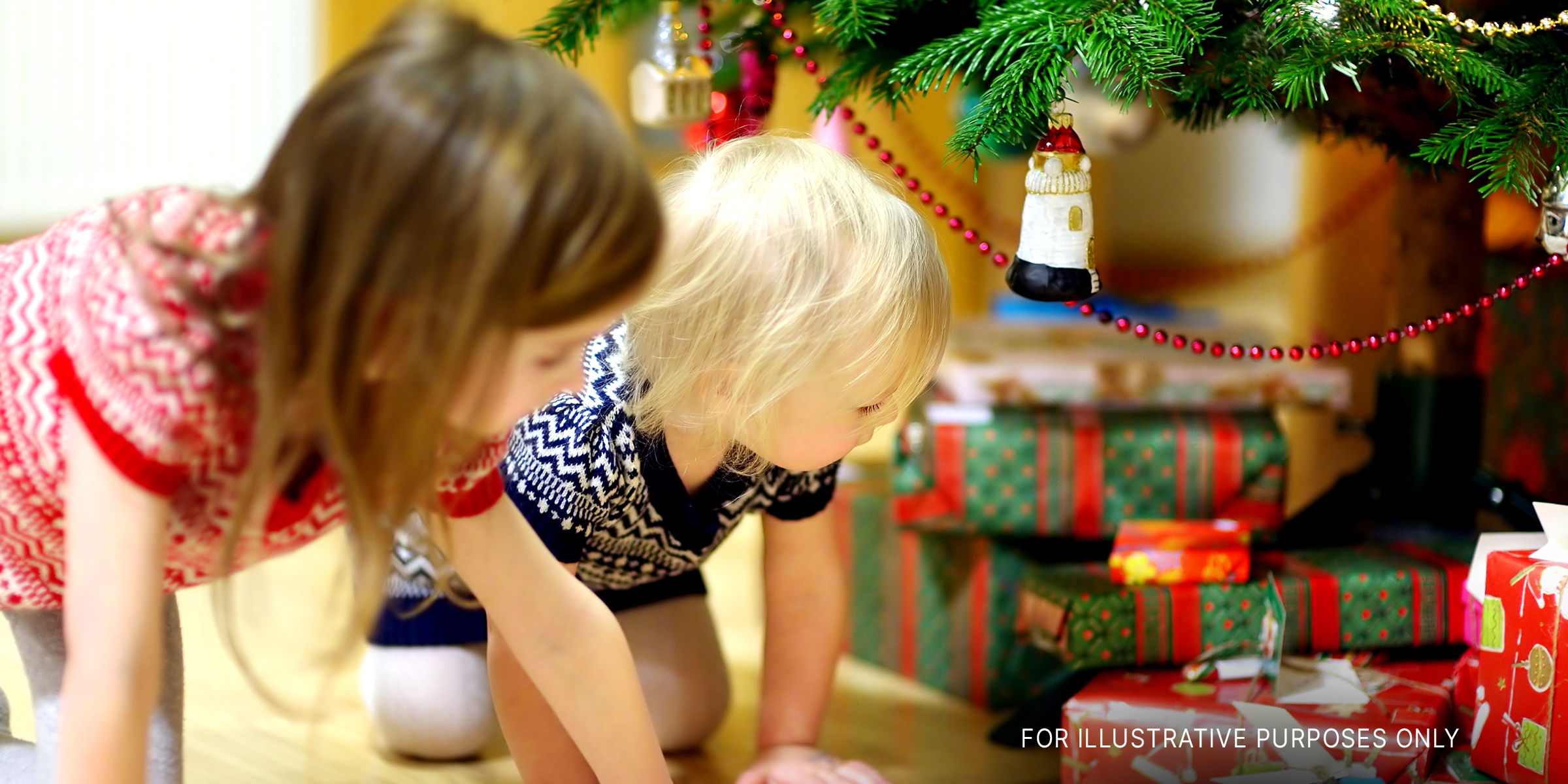 Children looking at gifts under the Christmas tree | Source: Shutterstock