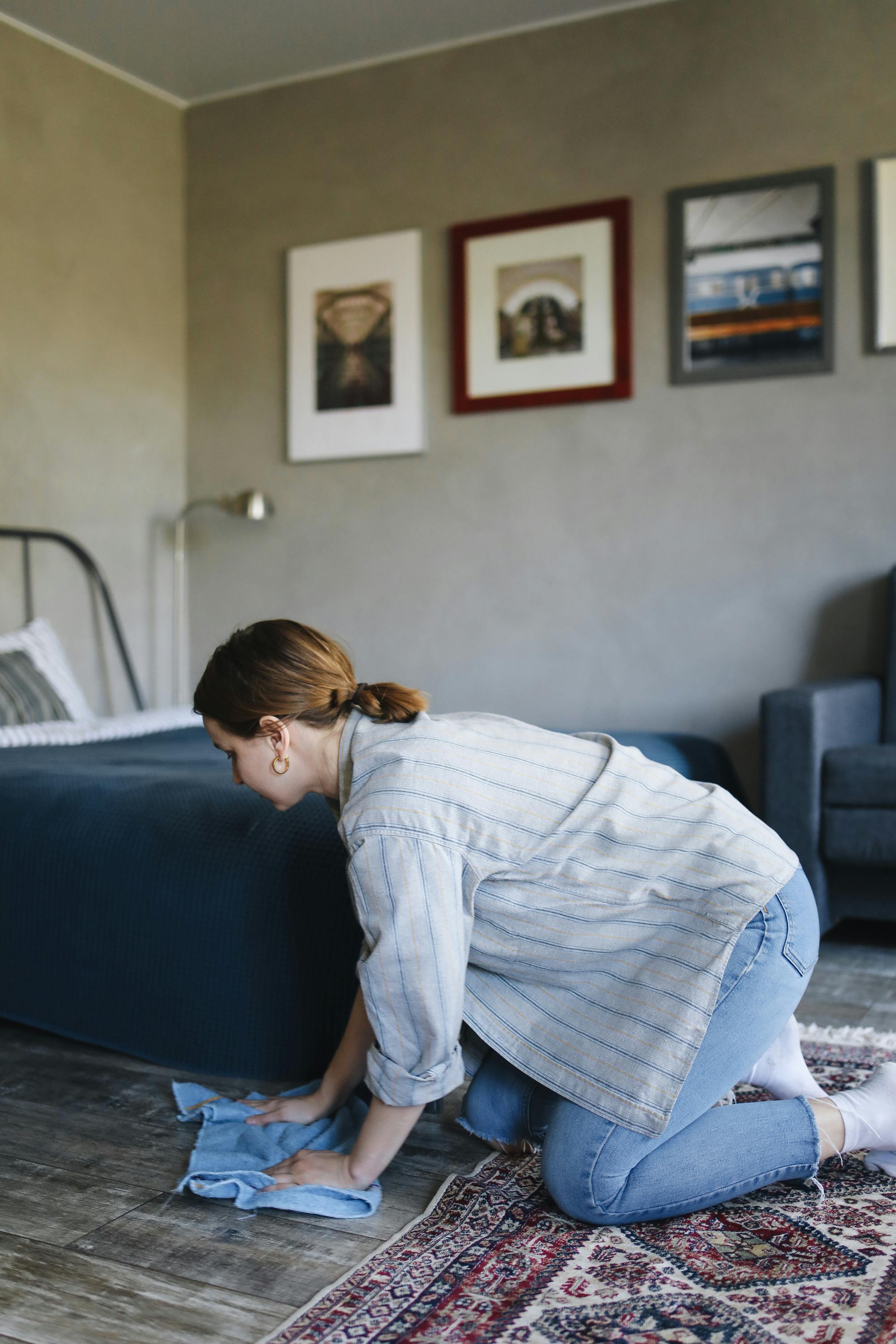 A woman cleaning the floor next to a carpet | Source: Pexels