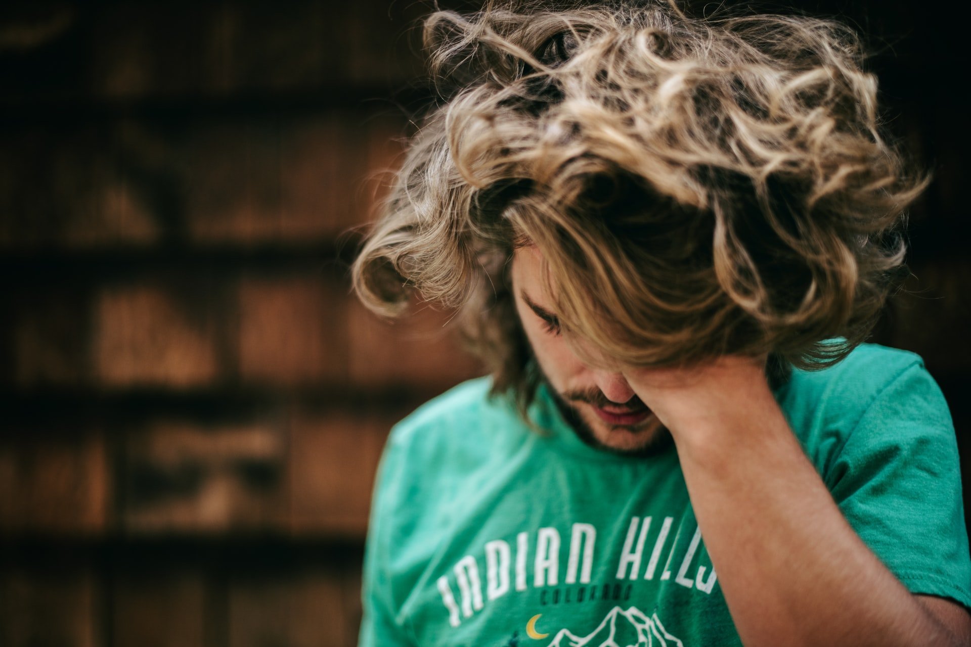 A man looking down while holding his hair | Source: Unsplash