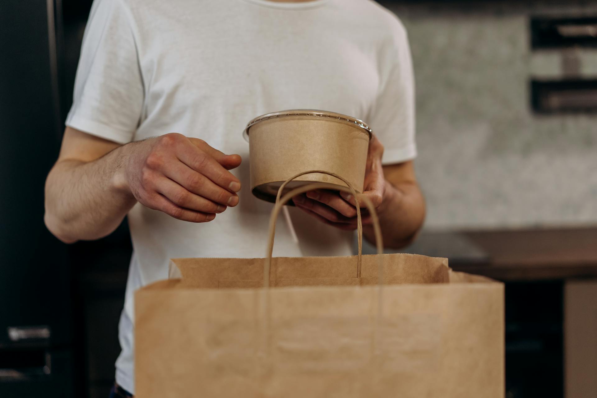 A man holding a paper bag and a container | Source: Pexels