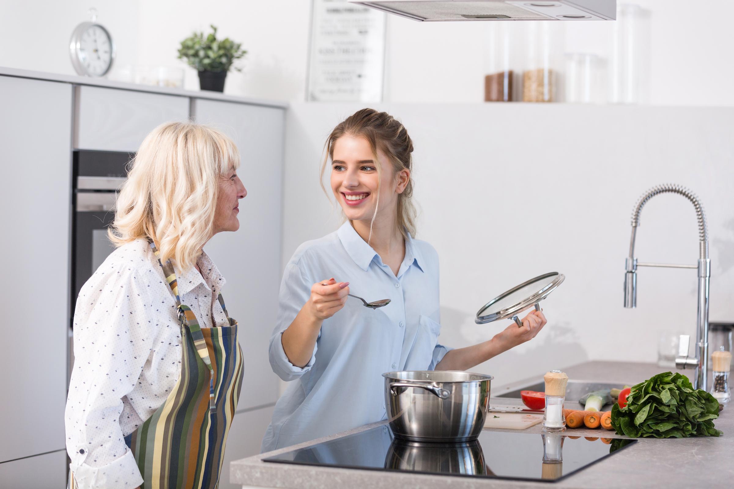 A smiling woman talking to an older woman in the kitchen | Source: Freepik