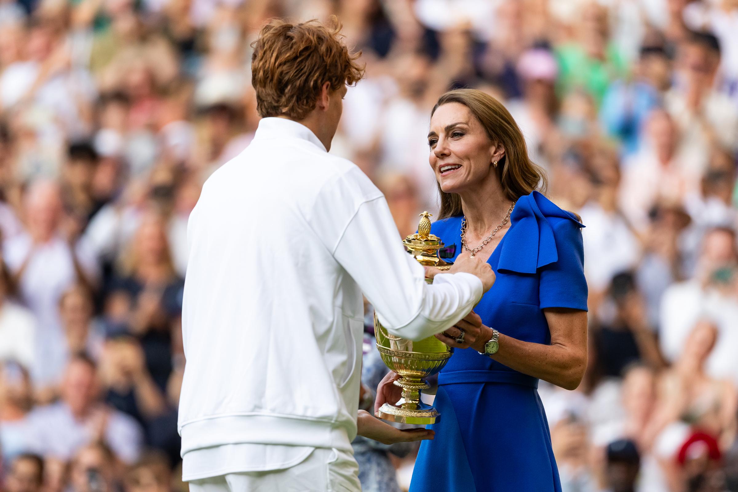 Princess Catherine presents the winner's trophy to Jannik Sinner following the Gentlemen's Singles Final. She meets his gaze with a smile as he accepts the award.