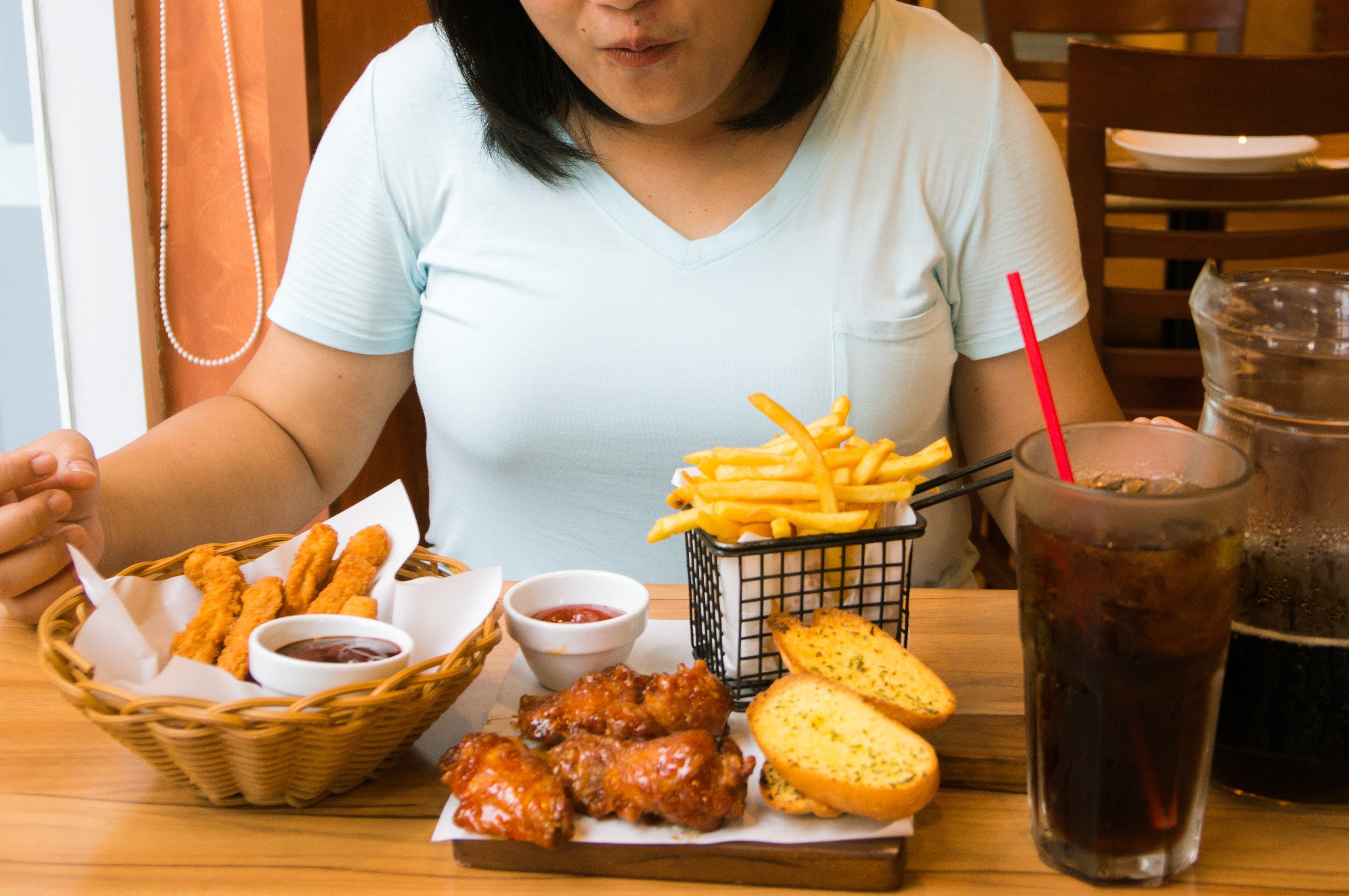Overweight woman eating junk food | Photo: Shutterstock.com