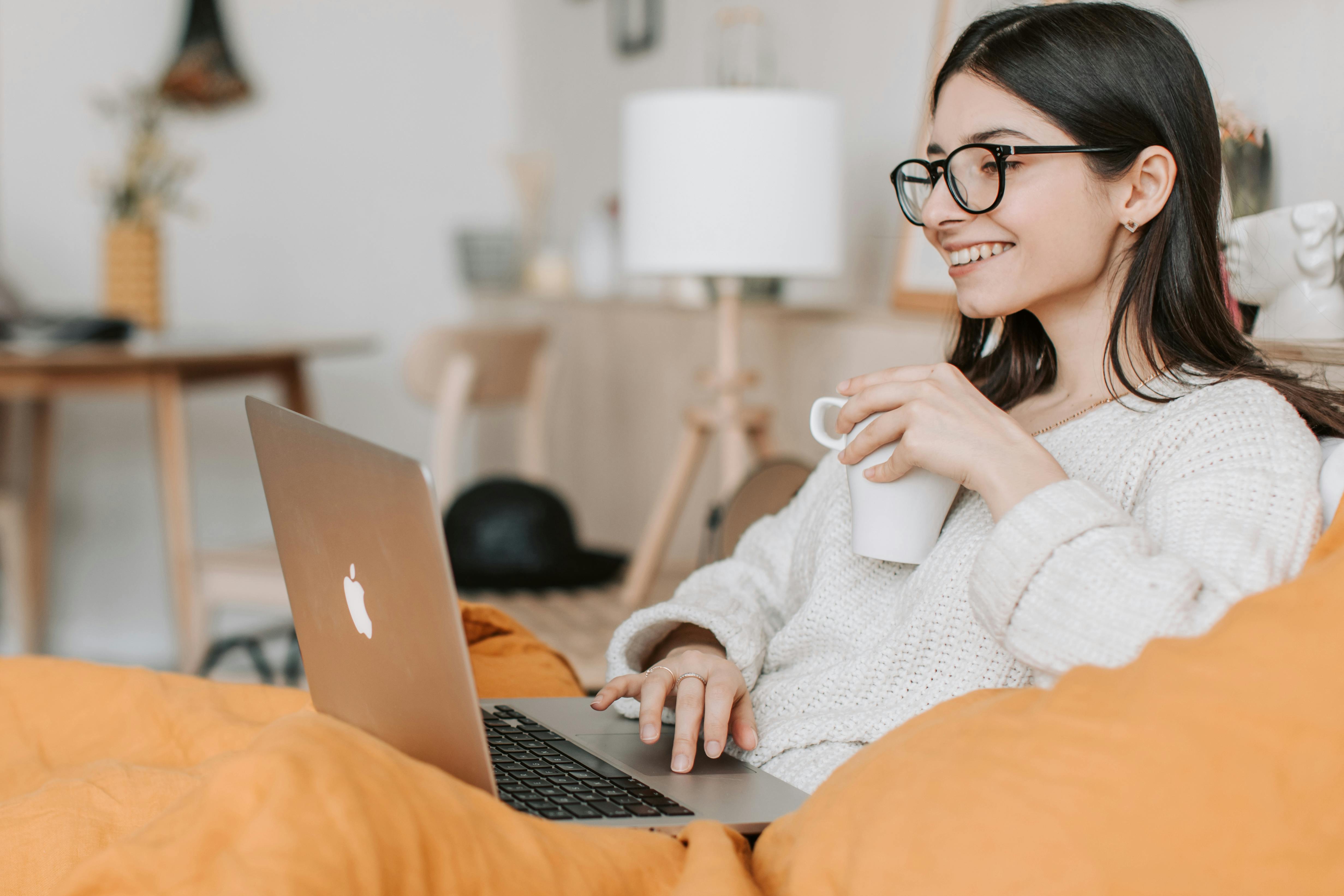 A woman smiles warmly while using her laptop | Source: Pexels