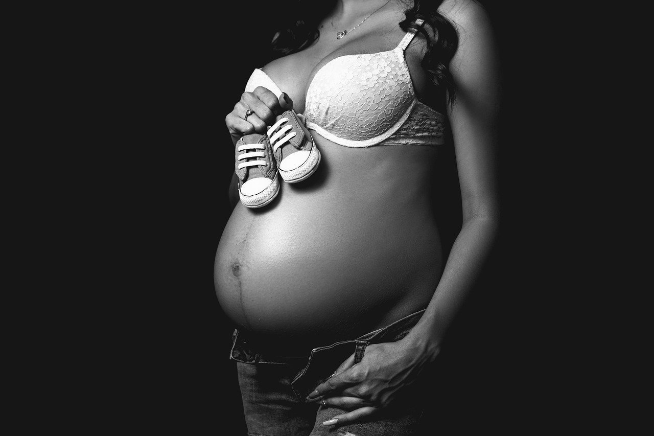 Une femme enceinte posant avec une petite chaussure. | Photo : Pixabay