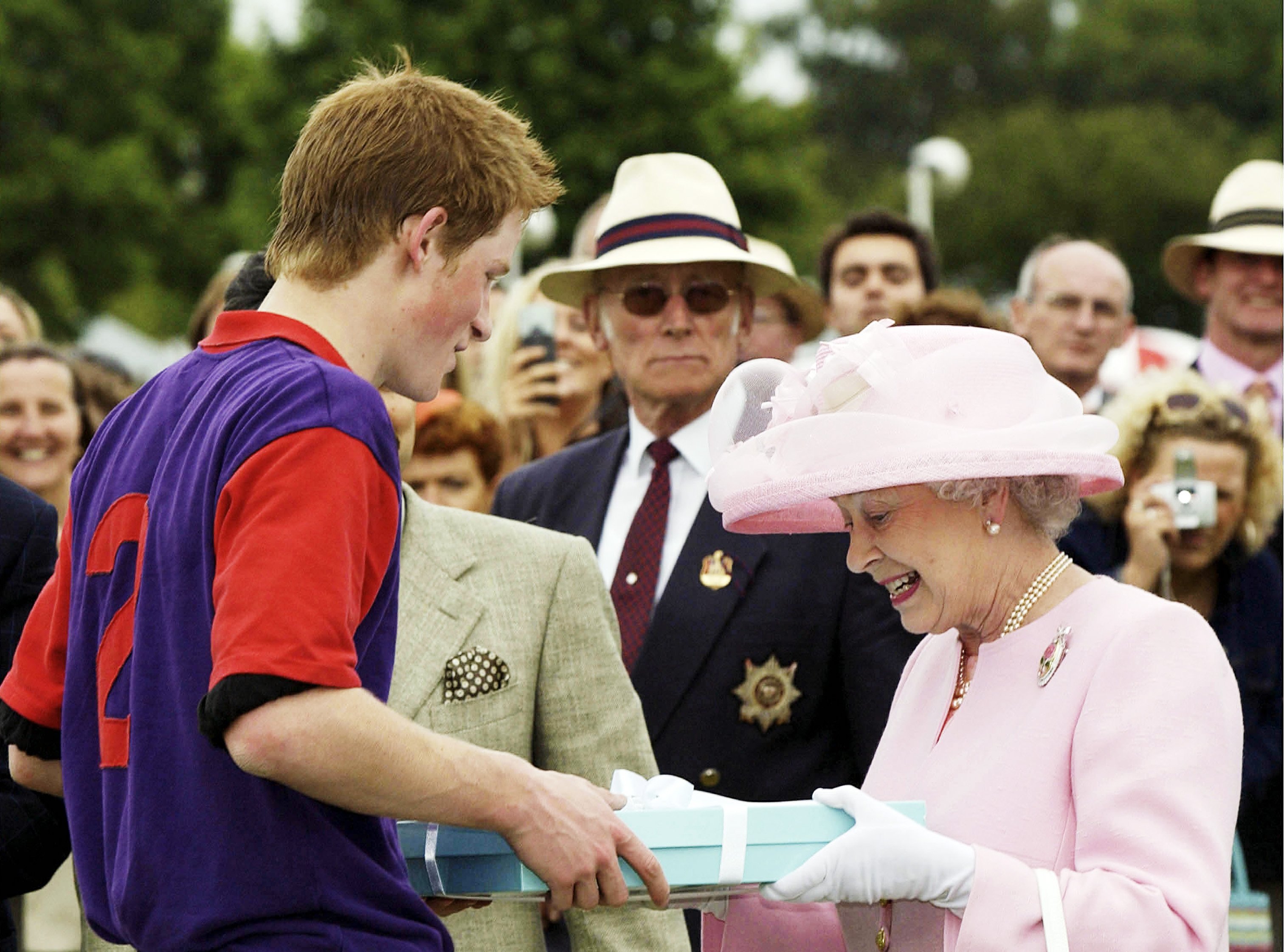 Königin Elizabeth II. hält Prinz Harry nach einem Polospiel während Royal Ascot am 18. Juni 2003 in Windsor, England, eine Präsentation | Quelle: Getty Images