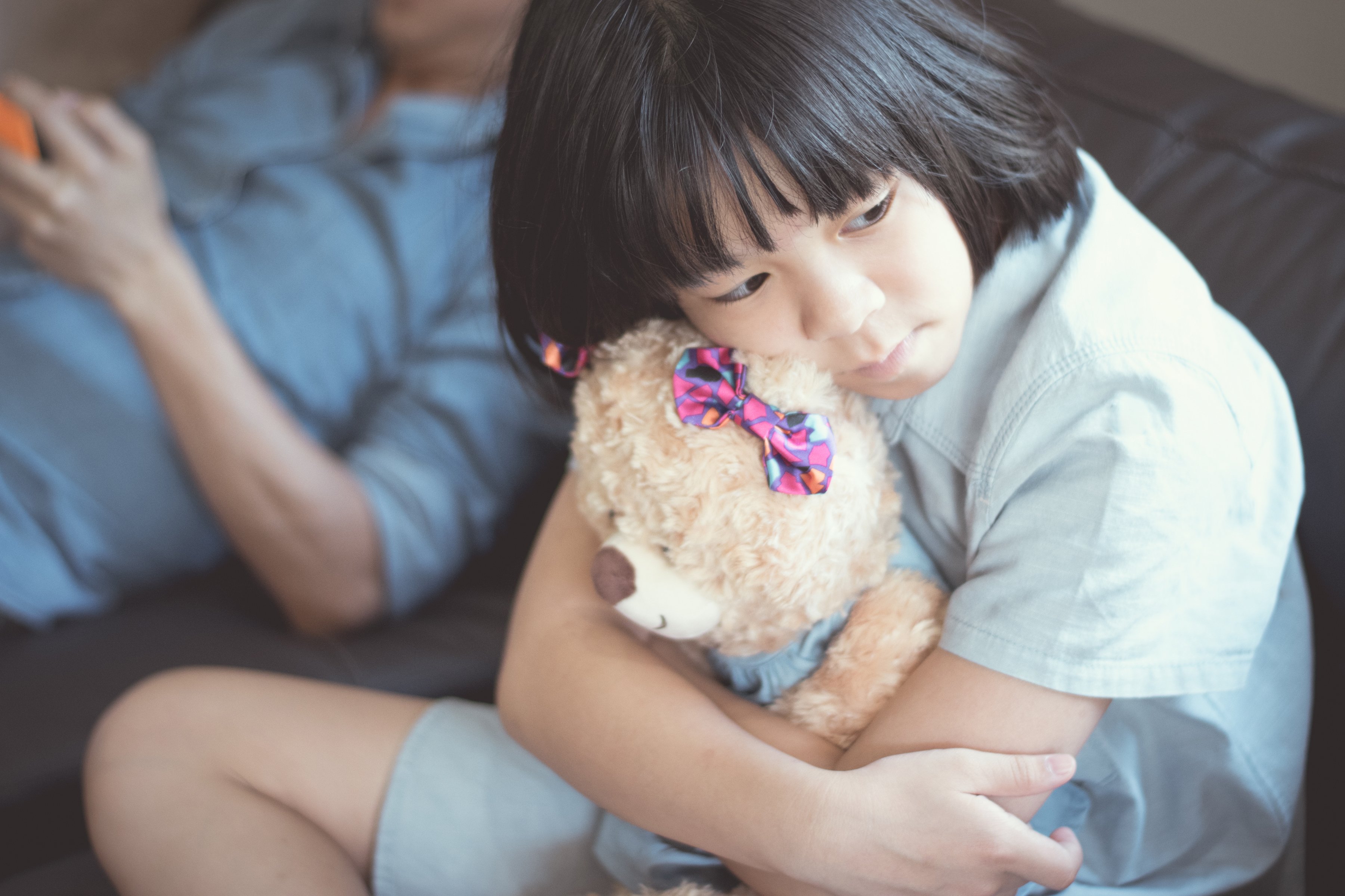 Niña triste abrazando un oso de peluche. | Foto: Shutterstock