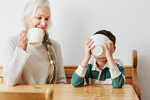 A young boy drinking coffee with his grandma | Photo: Getty Images