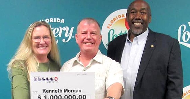 Kenneth Morgan standing in the middle of two individuals while partially holding up a sign showing off lottery winnings of $1 million from the Florida Lottery. | Source: twitter.com/Tuko_co_ke