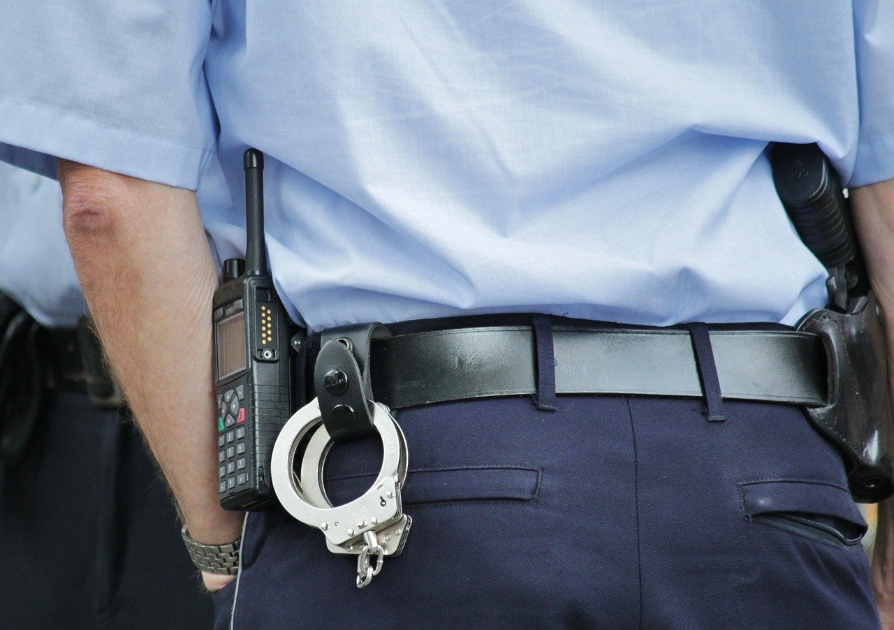 A picture of a police officer's back with a handcuff hanging from his belt. | Photo: Pixabay