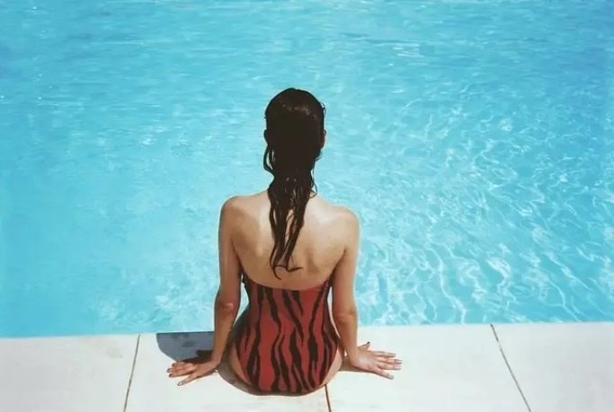 Mujer sentada en la orilla de una piscina. | Foto: Pixabay