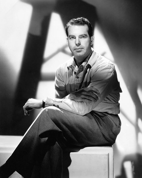 Fred MacMurray (1908-1991), US actor, sitting on a pedestal with his legs crossed, in a studio portrait, against background of shadows, circa 1950 | Photo: Getty Images