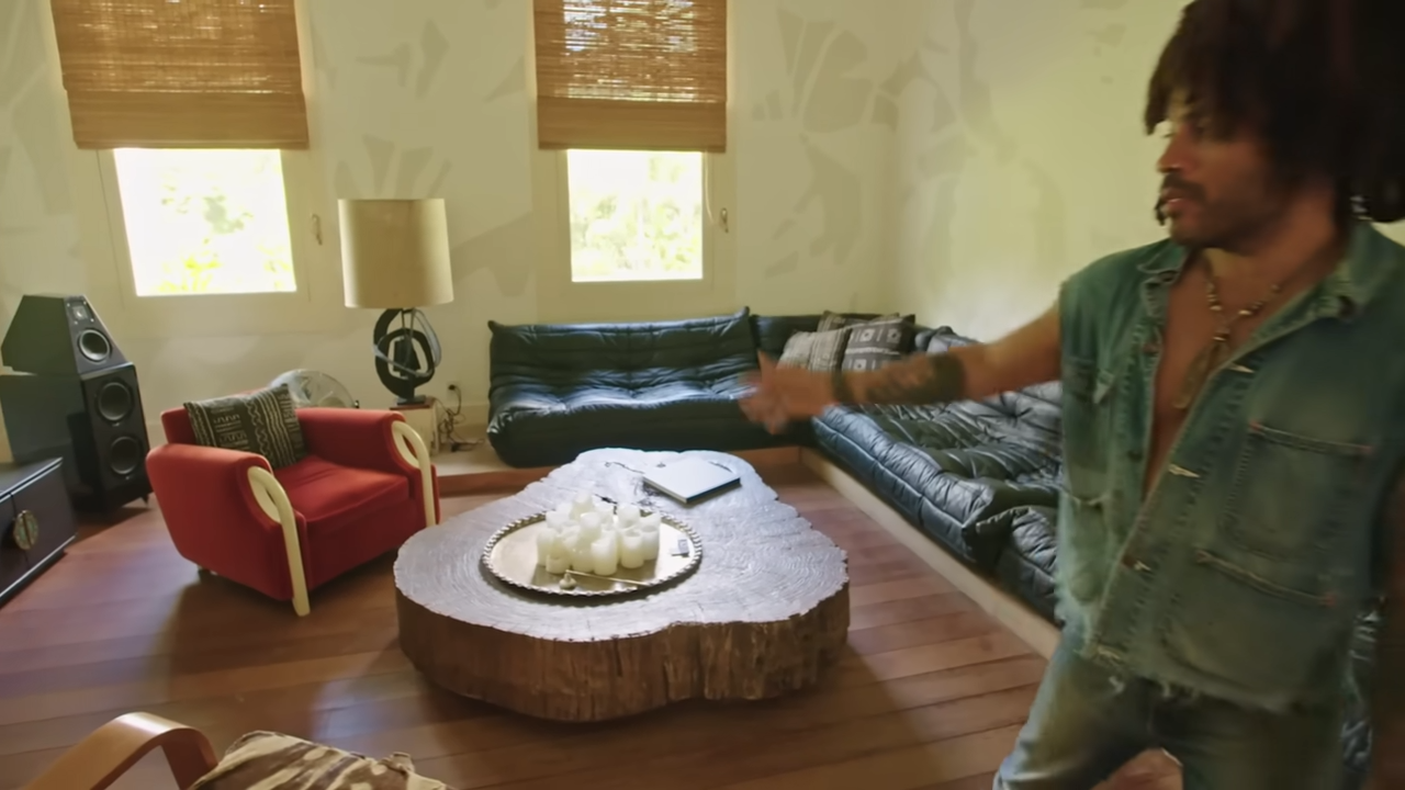 The main living room is styled with a black leather de Sede modular sofa, a massive tree-slice coffee table, and a bold red velvet armchair that once belonged to Andy Warhol. | Source: YouTube/@Archdigest
