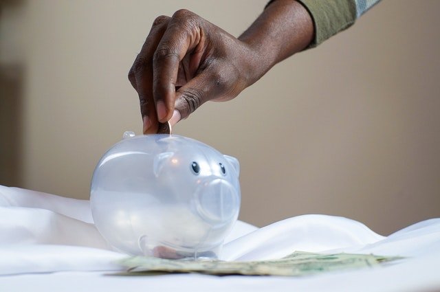Person putting coin in a piggy bank | Photo: Pexels