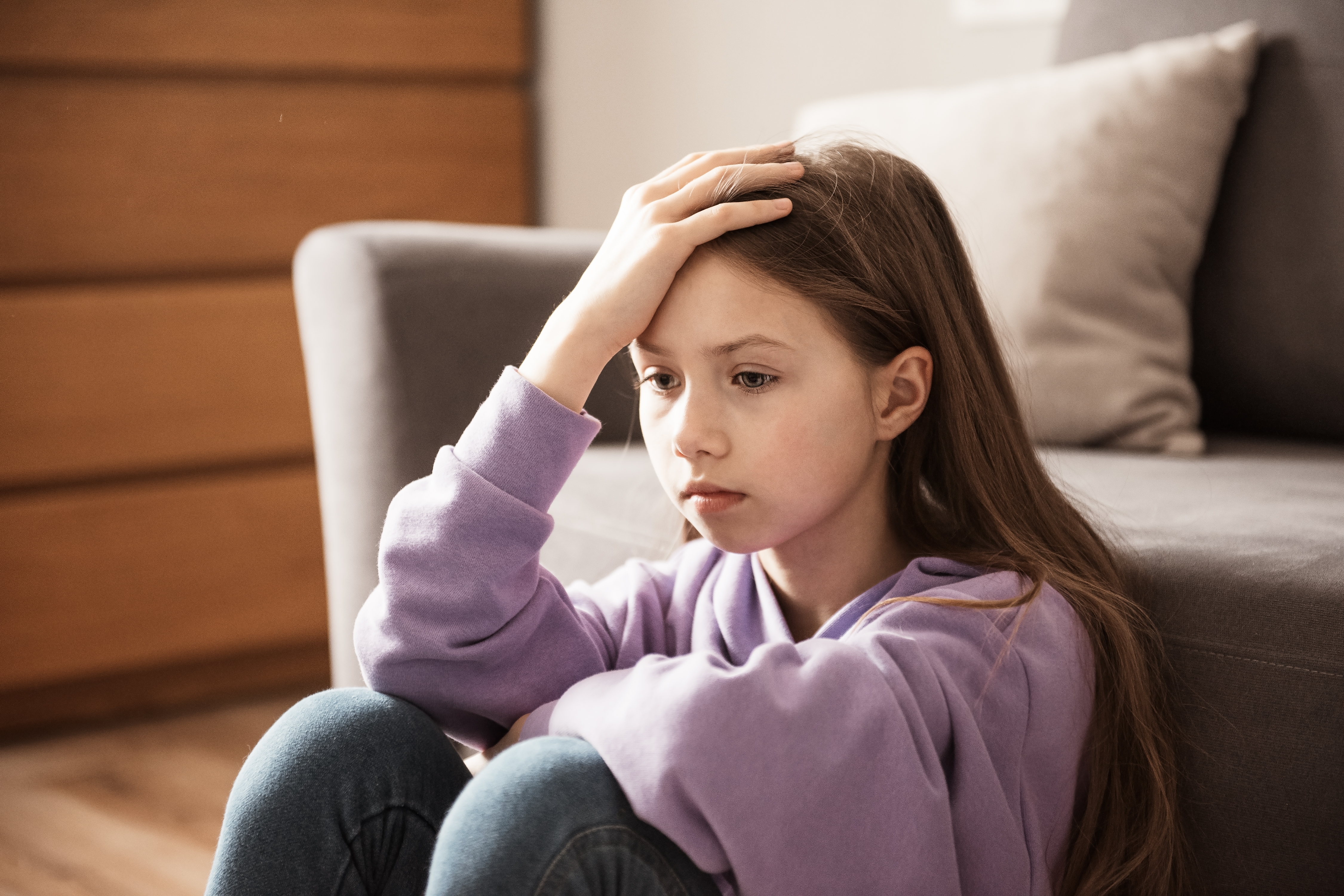 A depressed teenage girl is pictured sitting indoors | Source: Shutterstock
