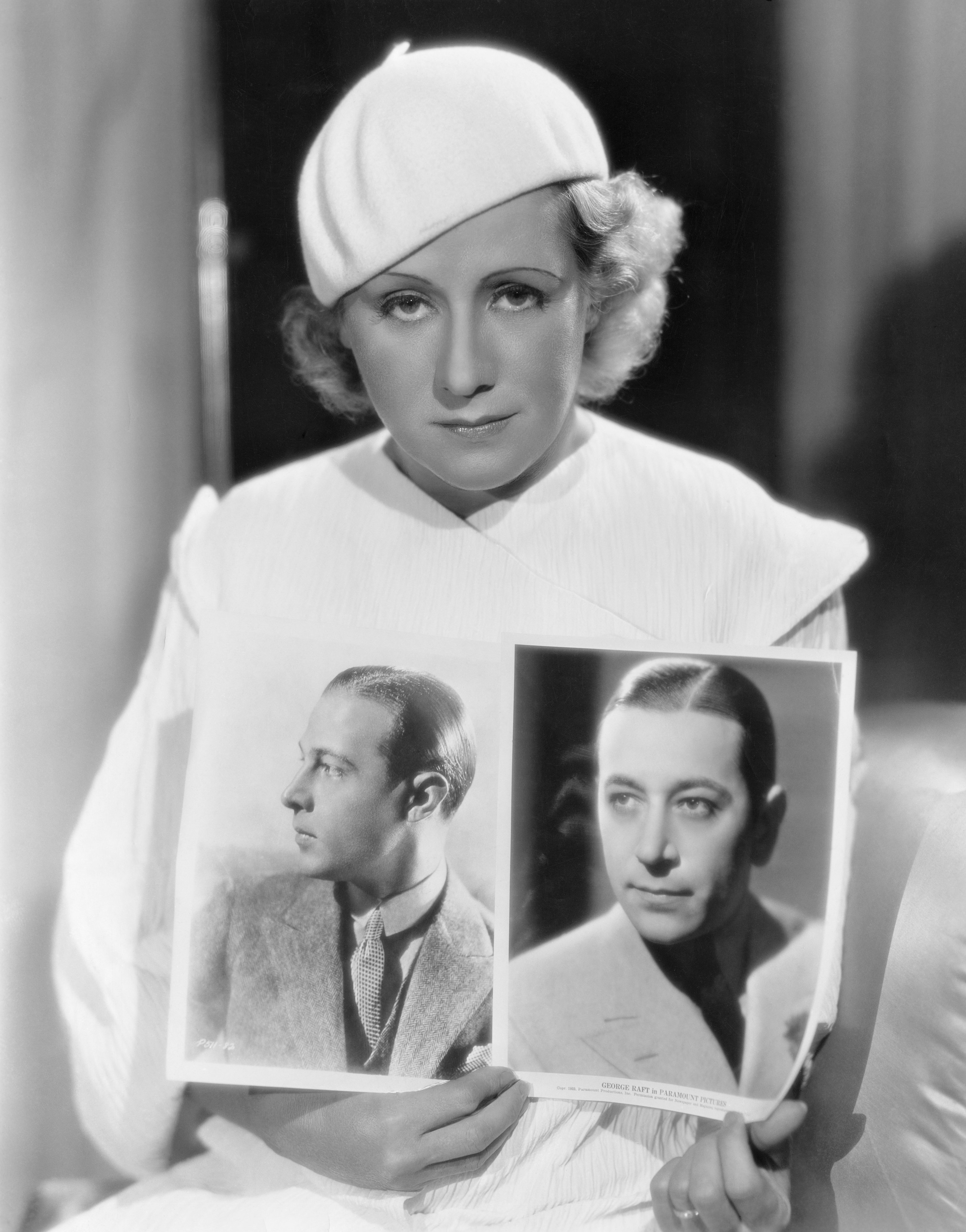 Jean Acker held up photos of her late ex-husband Rudolph Valentino and George Raft for comparison on 01 January, 1933 | Photo: Getty Images