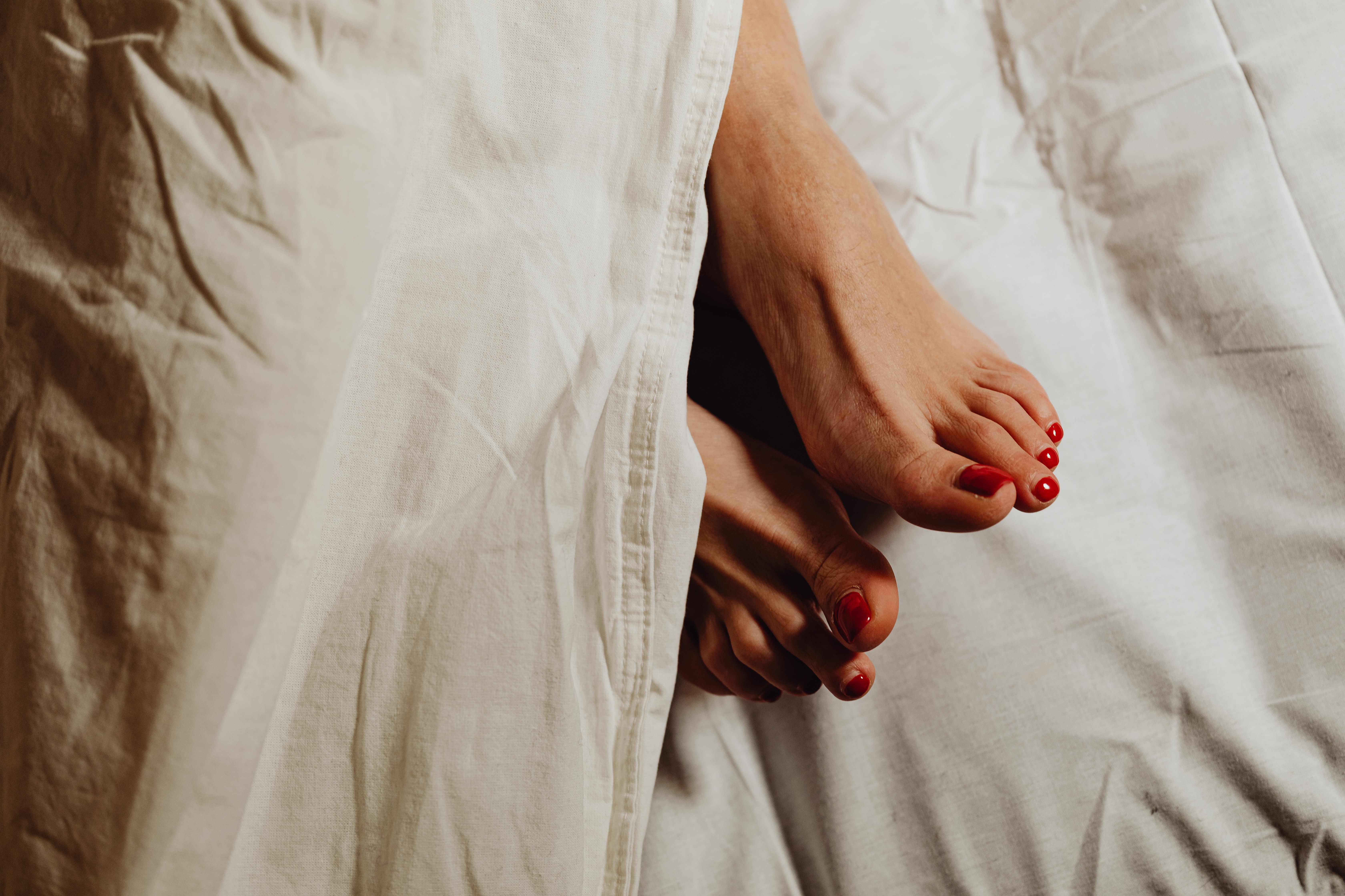 A picture of a woman's feet under sheet covers | Source: Pexels