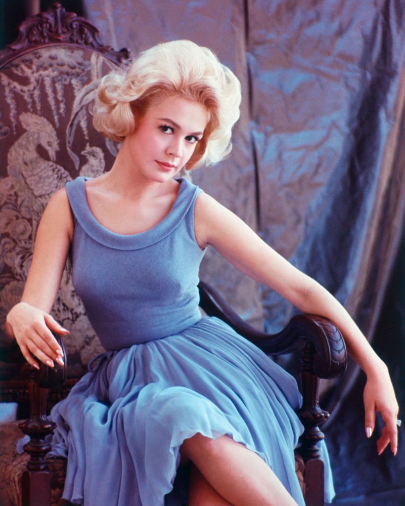 US actress Sandra Dee wearing a sleeveless blue dress and sitting in a tapestry chair, circa 1965. | Photo: Getty Images