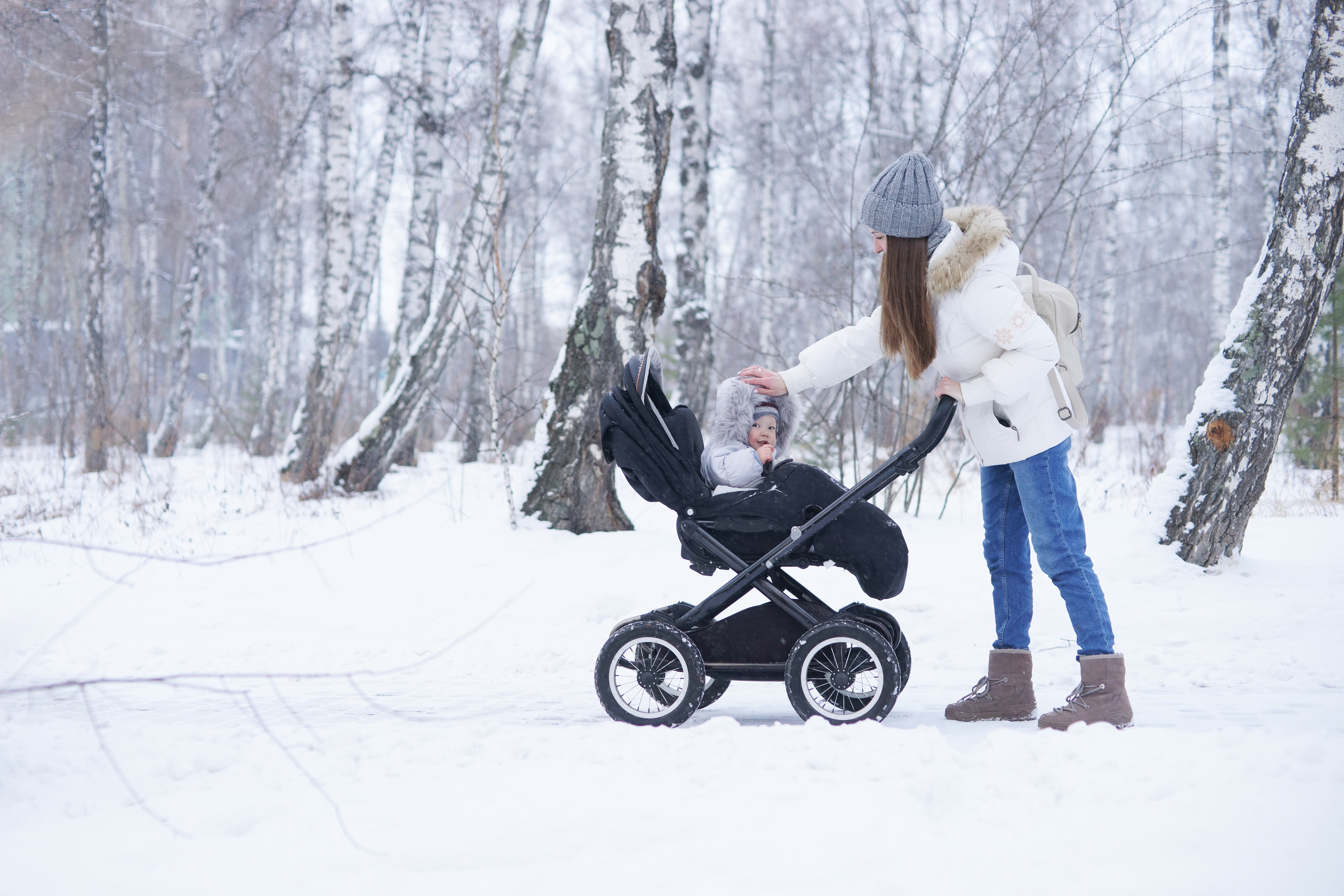 Young beautiful mother walking with her child in stroller in winter park | Source: Shutterstock