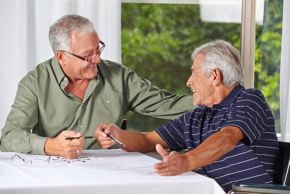 Two happy senior men solving crossword puzzle. | Photo: Shutterstock.