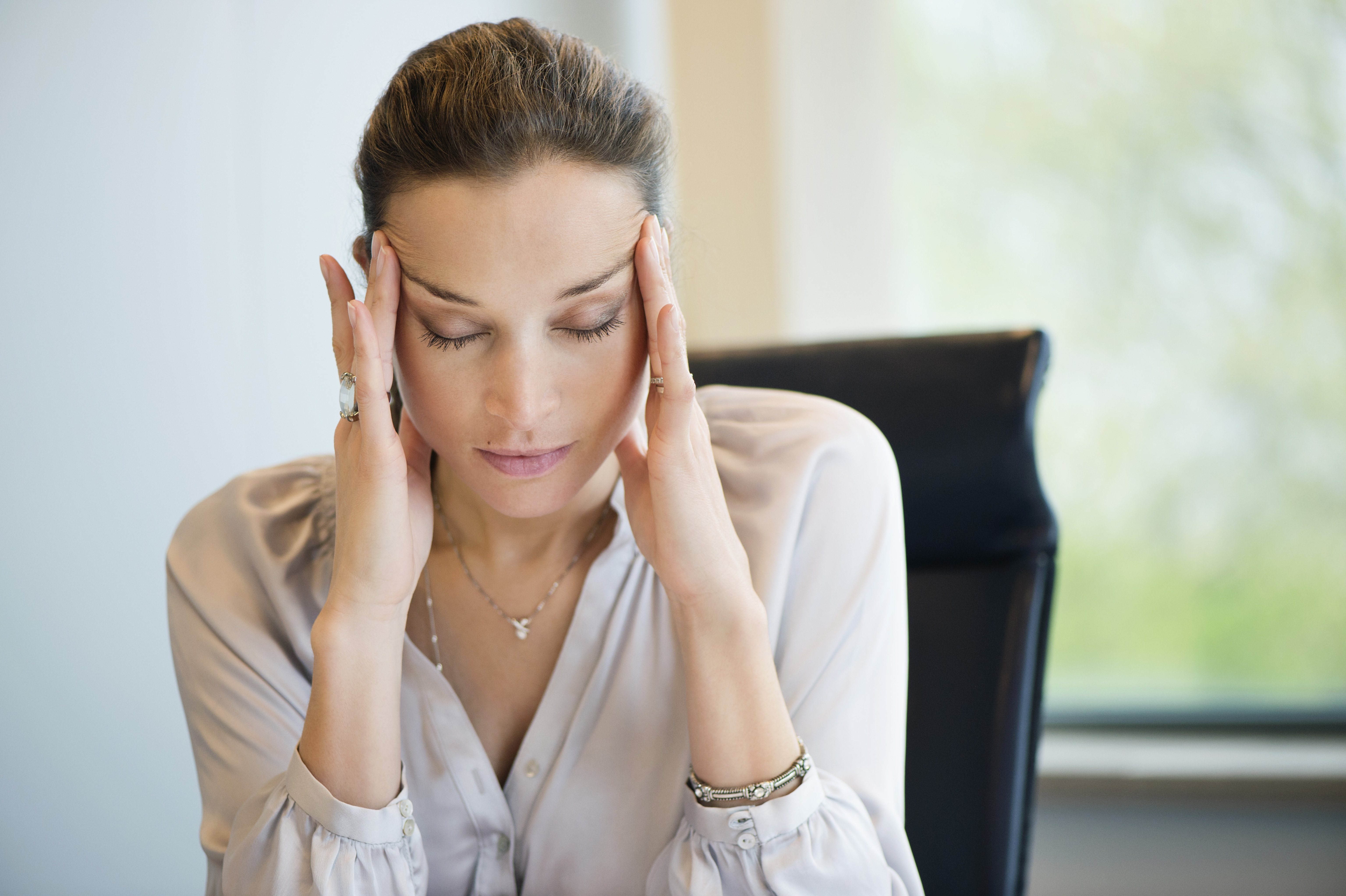 Woman suffering from a headache while working in an office | Source: Getty Images