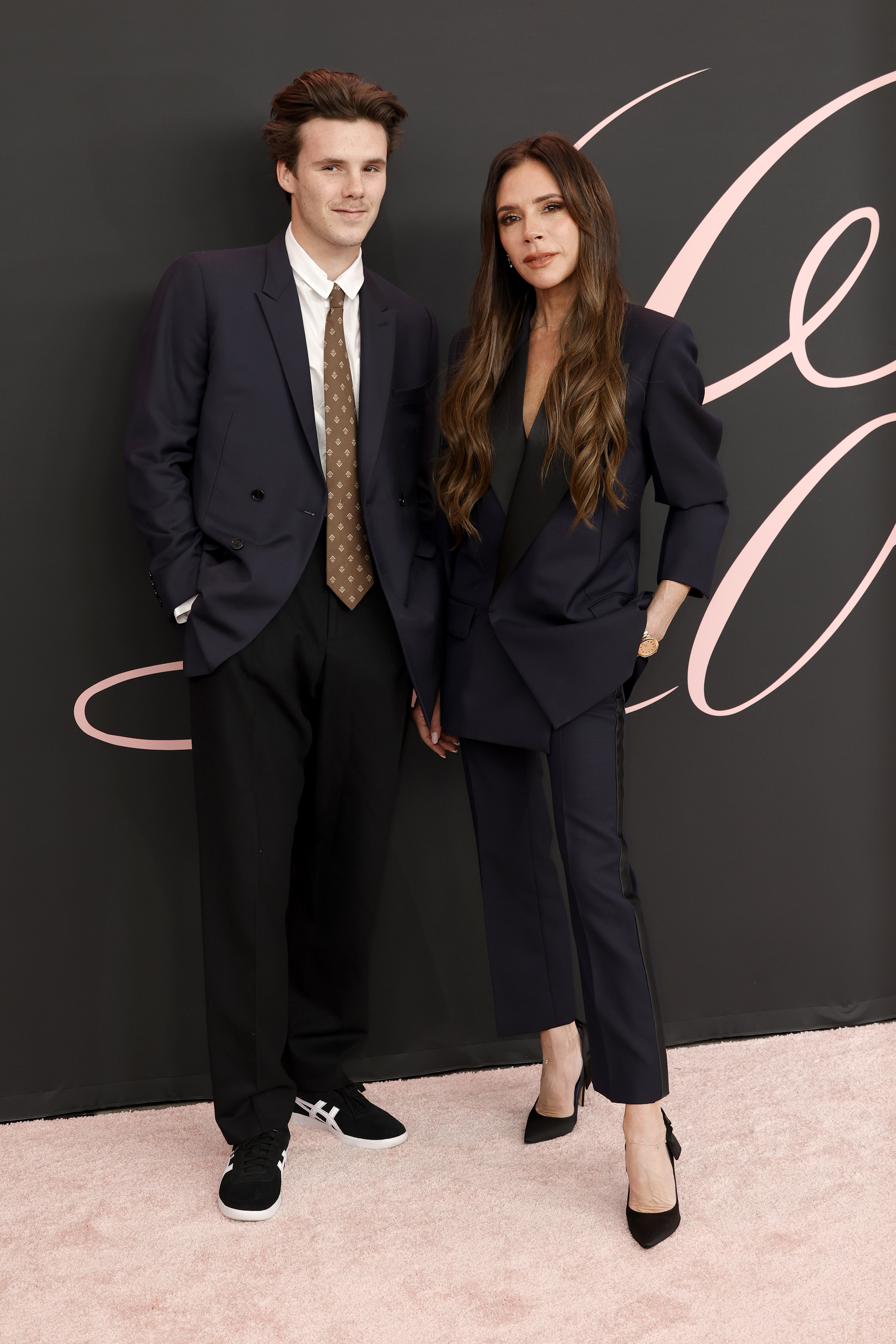 Cruz Beckham and his mother, Victoria Beckham, make a polished appearance at the premiere of "Lola" at the Regency Bruin Theatre in Los Angeles on 3 February 2024, stepping onto the pink carpet in coordinated dark ensembles that reflect the family's signature understated style.