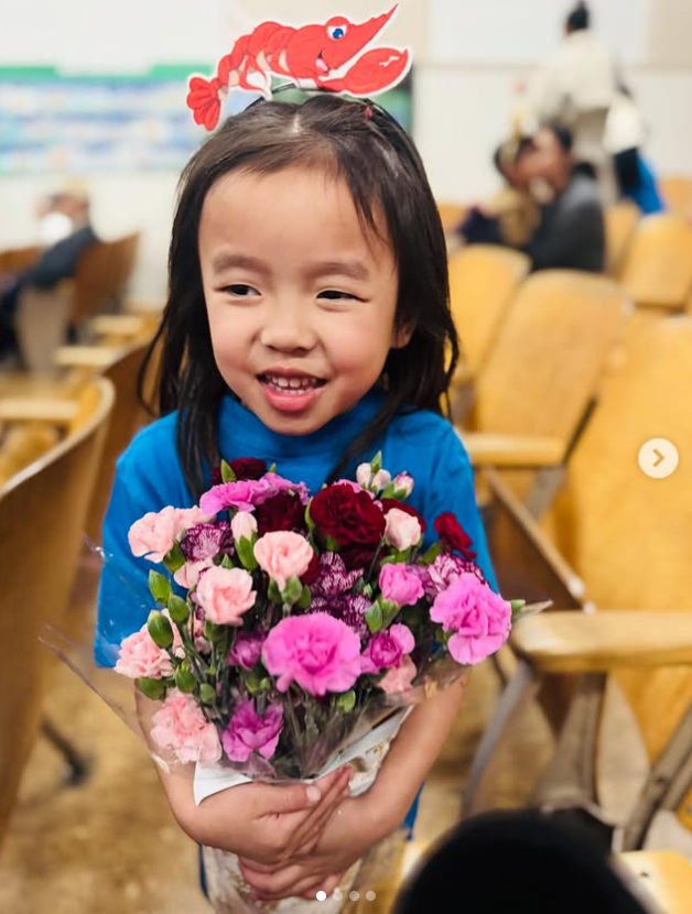 Everest Duong beams with pride, clutching a vibrant bouquet of pink and red flowers, from a Alex's post dated December 13, 2025. | Source: Instagram/xtinahuong