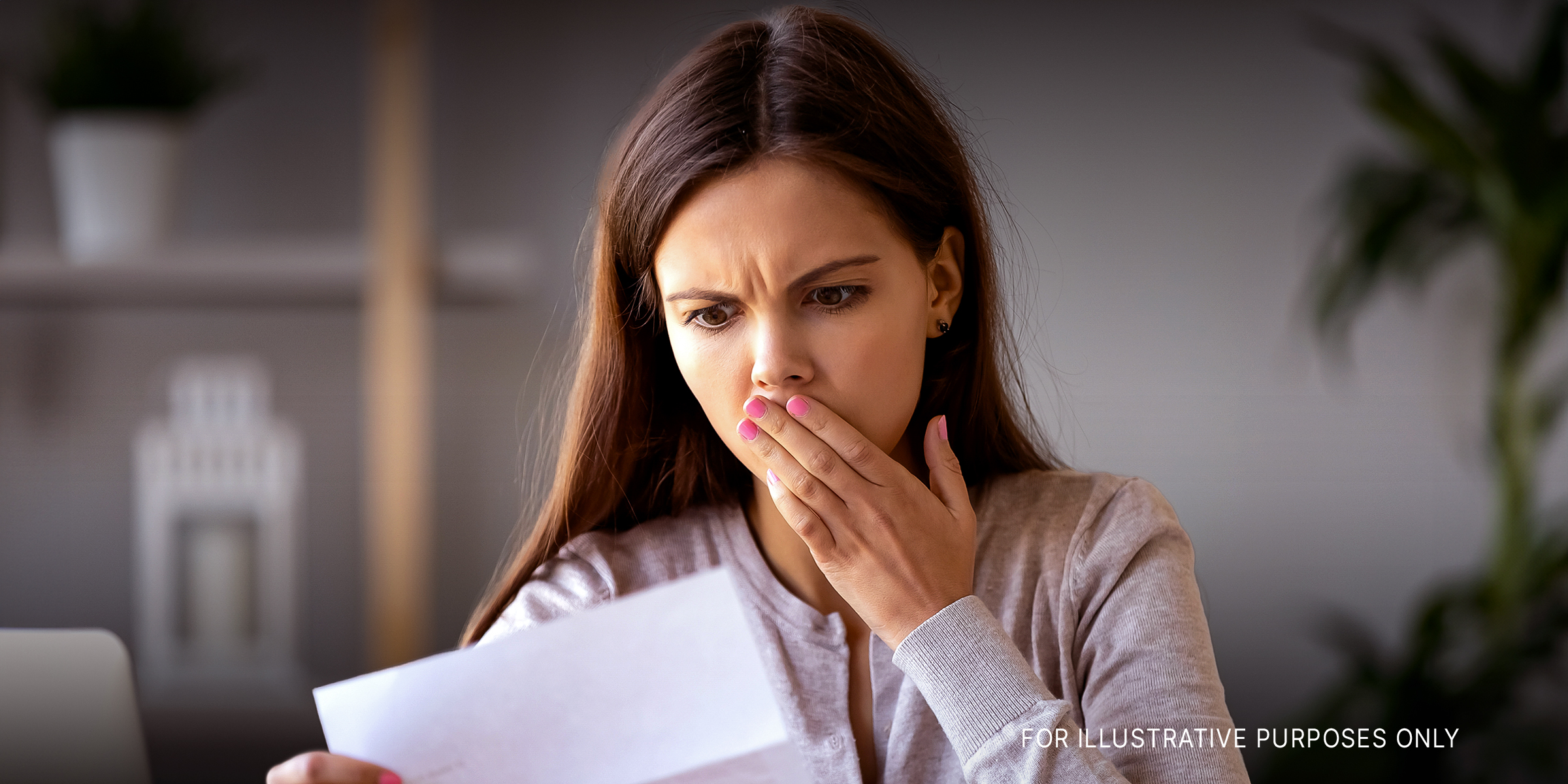 A shocked woman looking at a letter | Source: Shutterstock