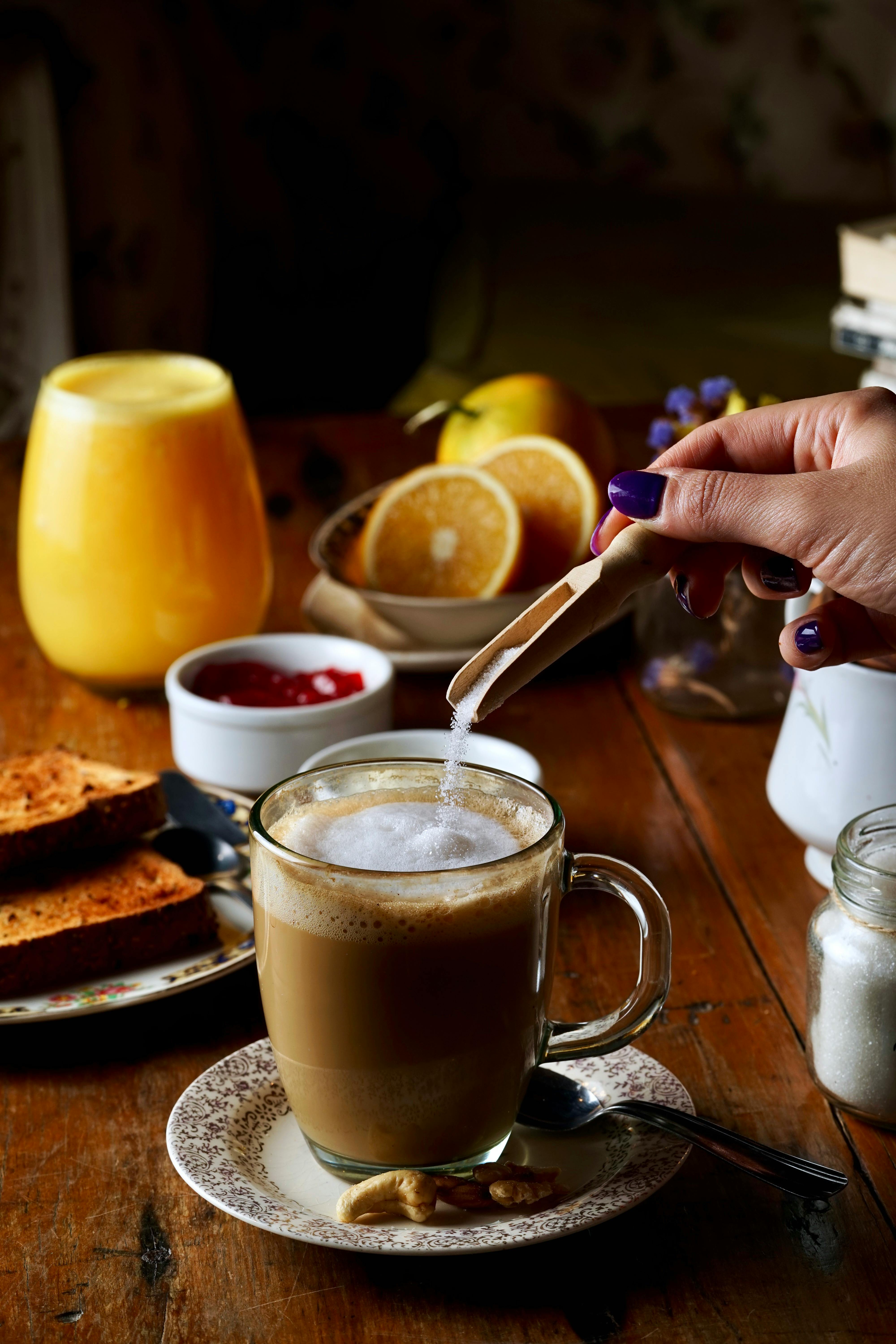 A woman adding sugar to her coffee | Source: Pexels