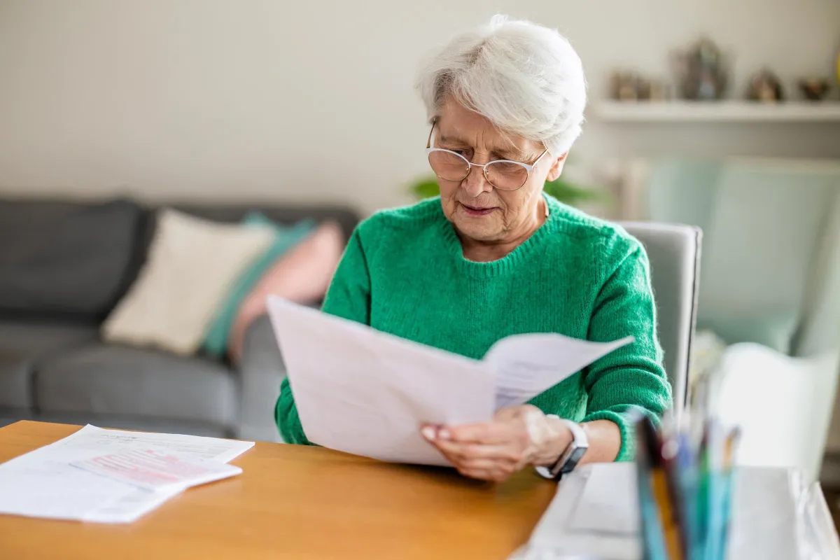 Senior woman sitting in the living room and doing paperwork | Source: Shutterstock