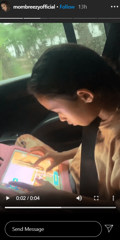 A picture of Royalty sitting in a car and using her tab. | Photo: Instagram/Mombreezyofficial