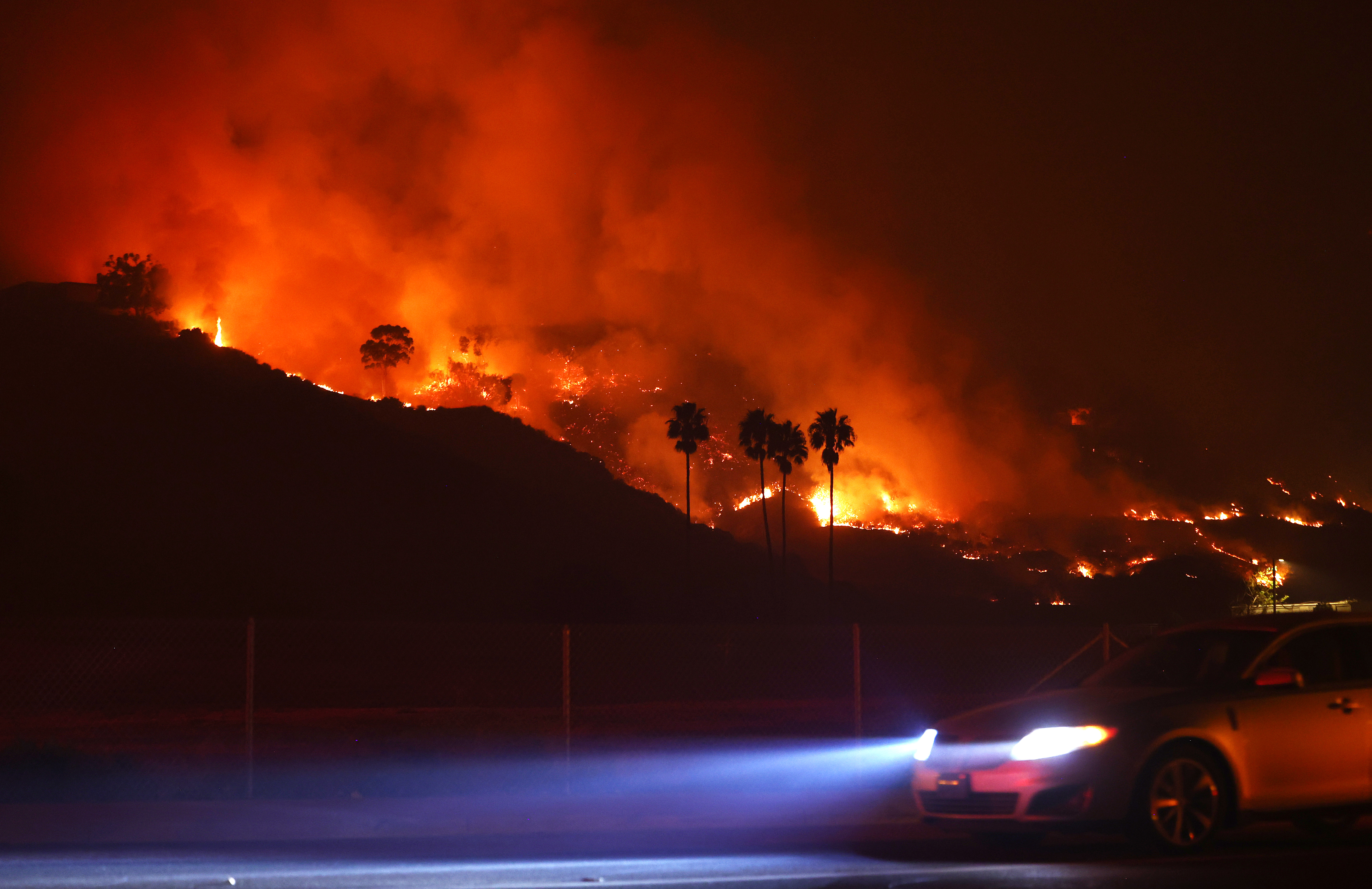 A car drives as the Franklin Fire burns in Malibu, California, on December 10, 2024 | Source: Getty Images