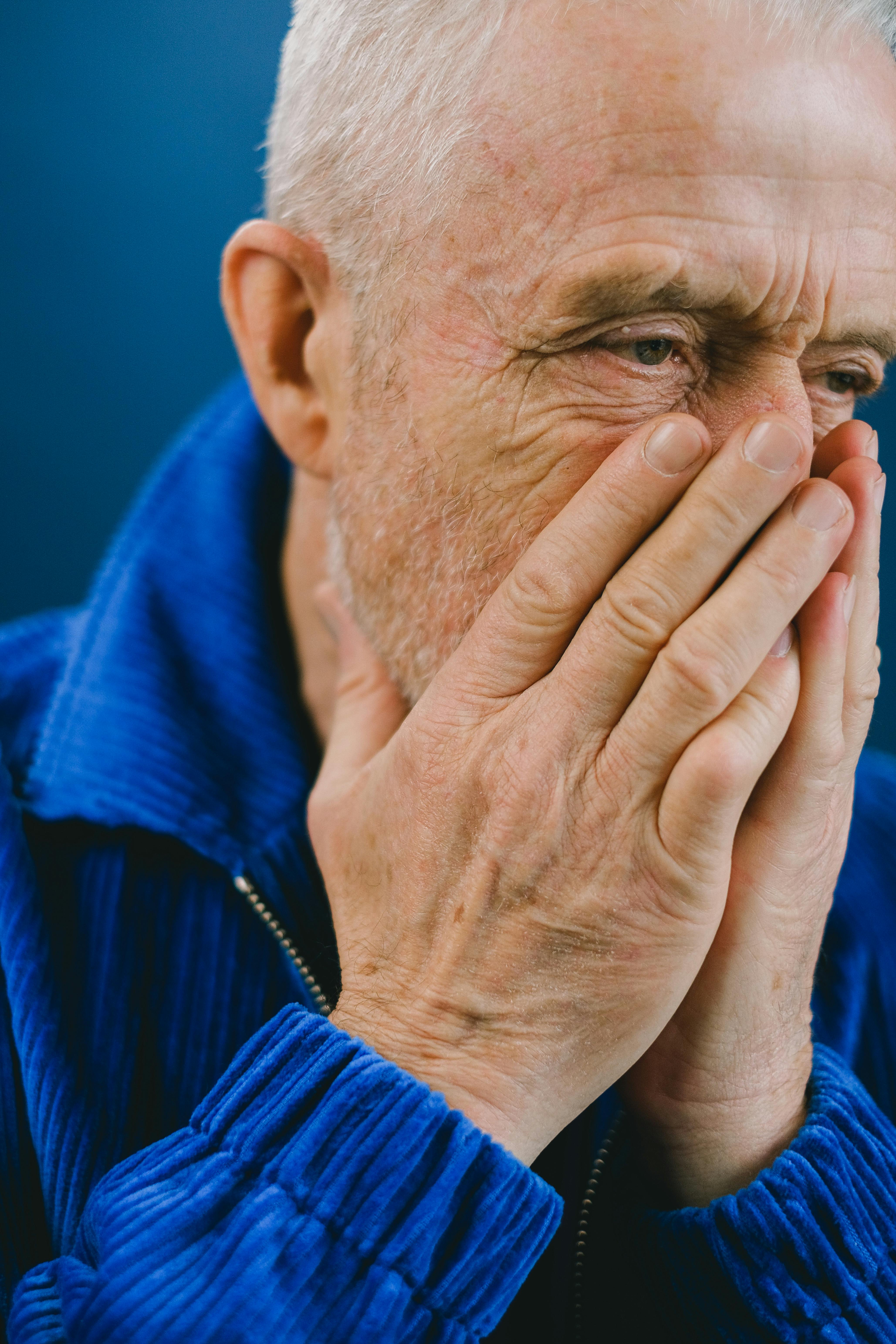 An upset older man covering his mouth and nose with his hands | Source: Pexels