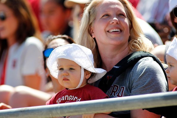 A young woman pictured with her baby as they enjoy the warm weather during a sports game | Photo: Getty Images