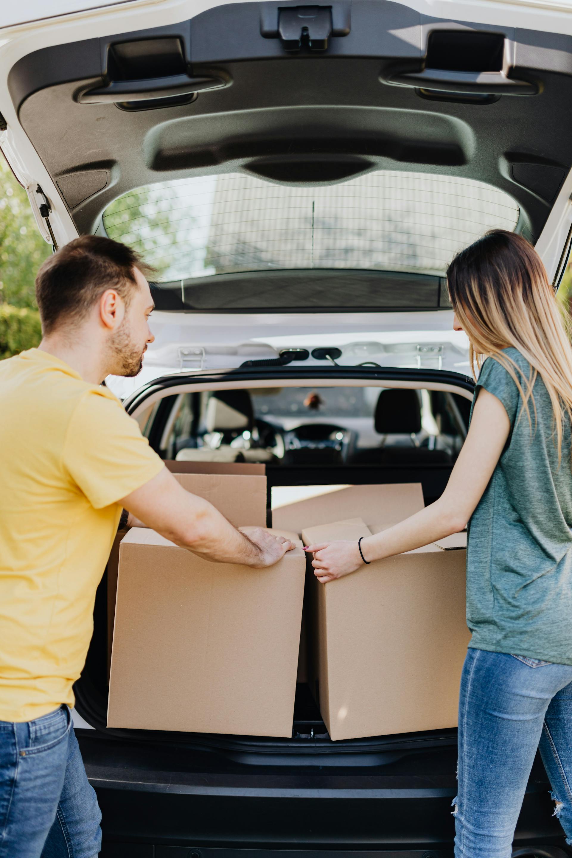 A couple taking out carton boxes from a car's trunk | Source: Pexels