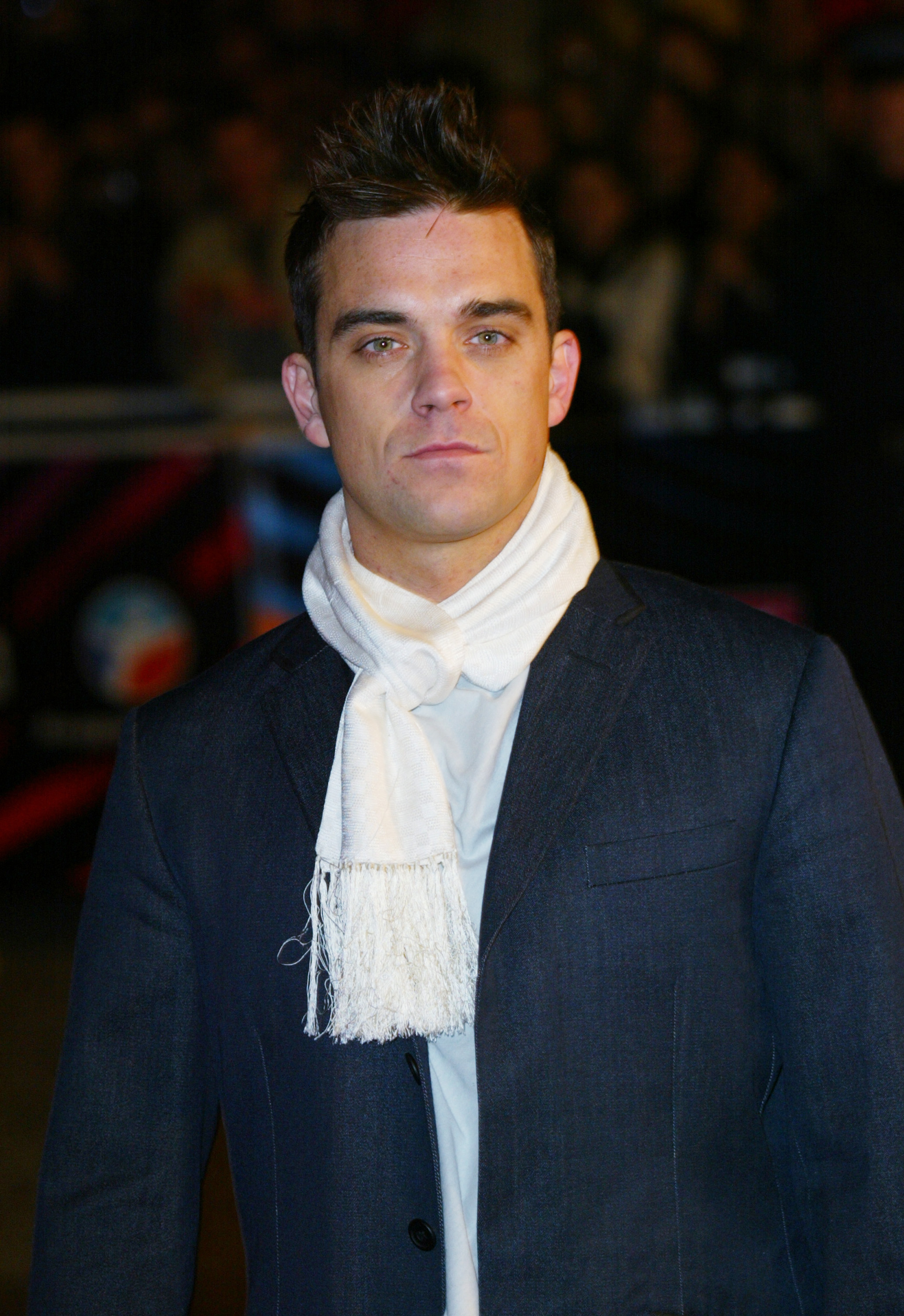 Robbie Williams attended the NRJ Music Awards in Cannes, France, in 2003, dressed in a tailored suit and white scarf. With a sleek look and serious expression, he embodied the polished confidence of a pop star at the peak of his international fame.