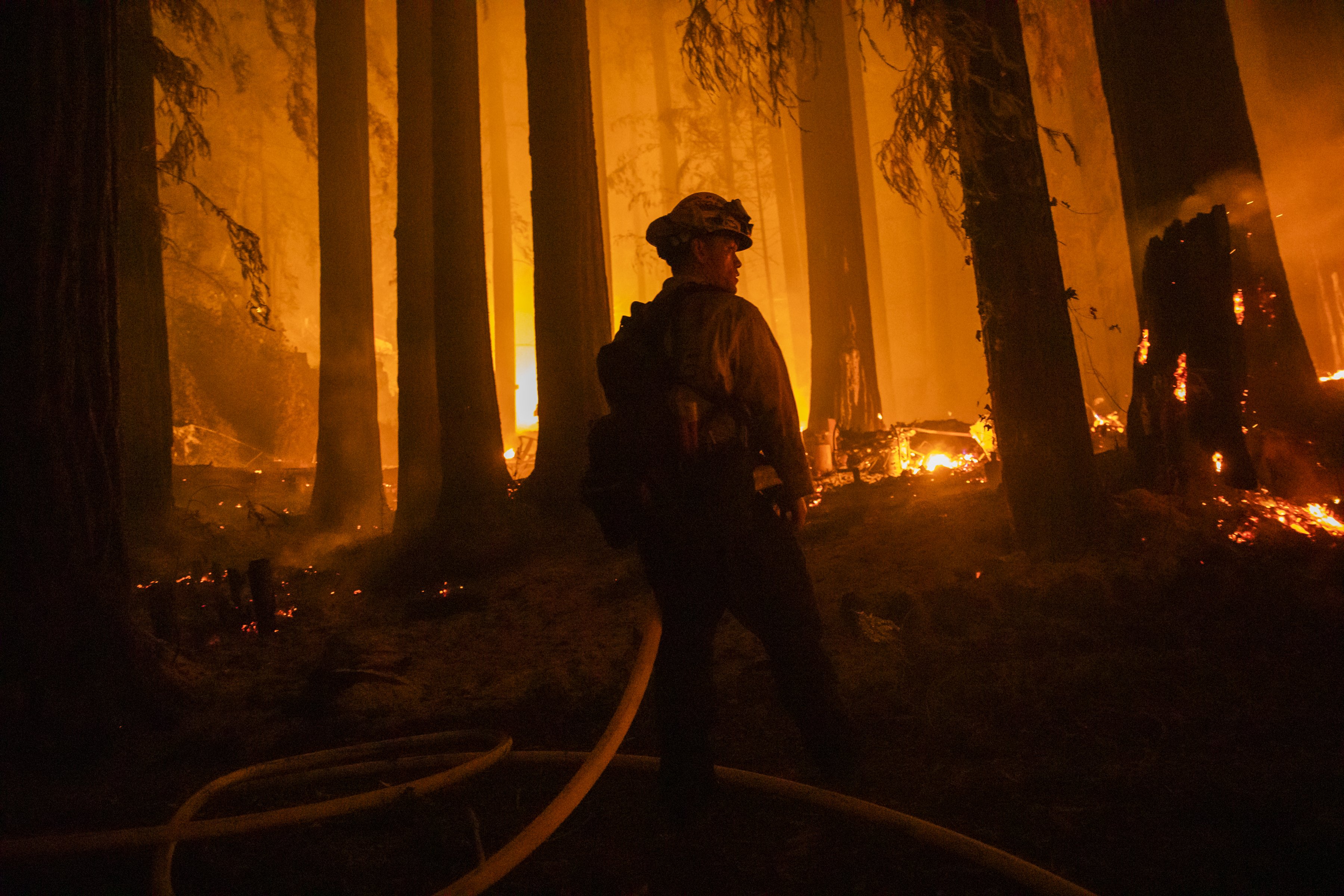 A firefighter with the Jameson Creek CDF station fights a fire on a property on Acorn Drive during the CZU Lightning Complex fire in Santa Cruz County, California, U.S., on Thursday, Aug. 20, 2020. | Source: Getty Images.