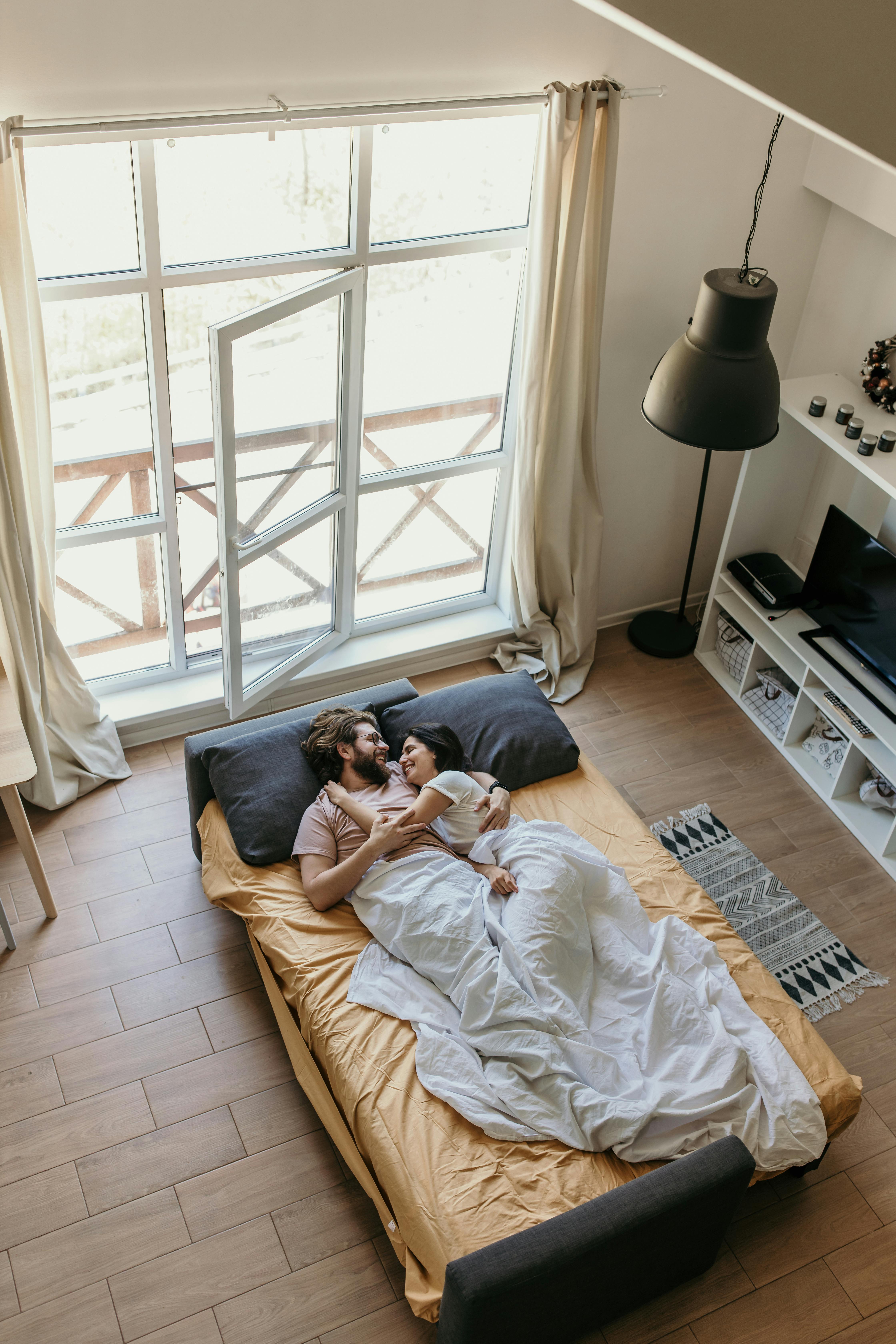 A happy couple laying in bed | Source: Pexels