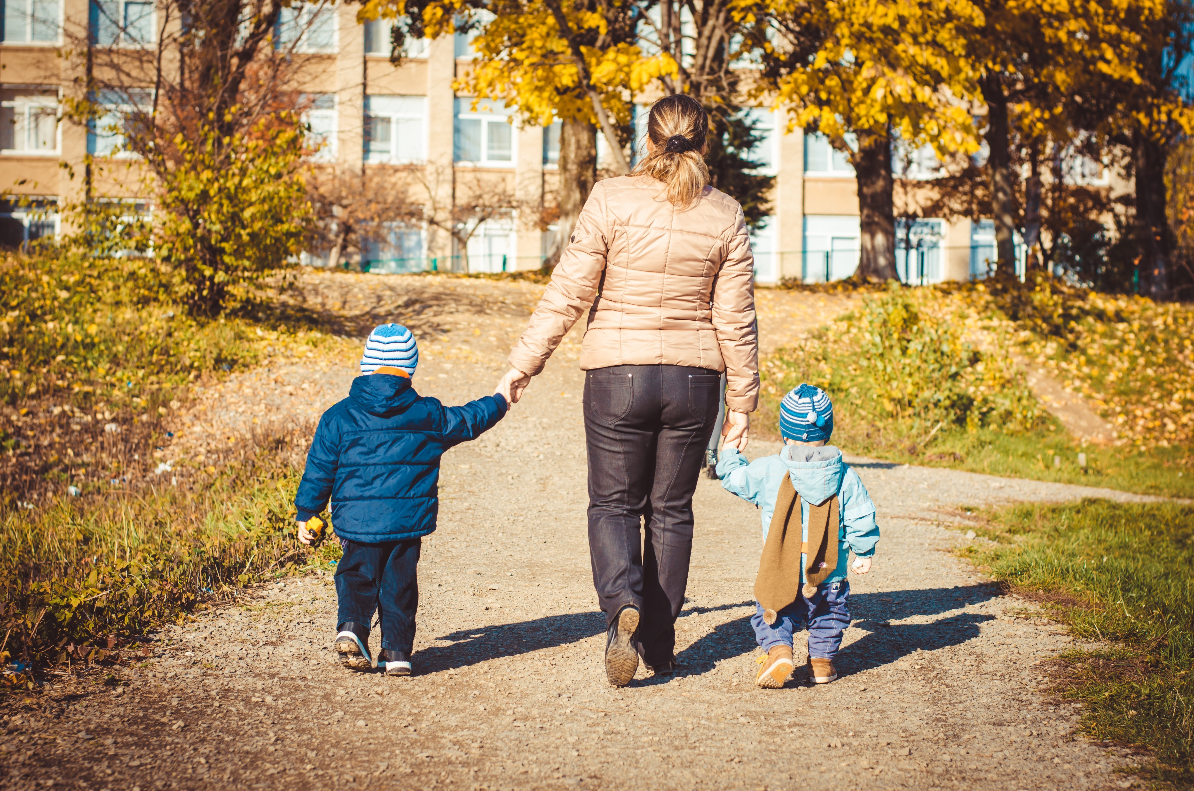Vue arrière d'une mère et de deux filles marchant ensemble en se tenant la main | Photo : Shutterstock