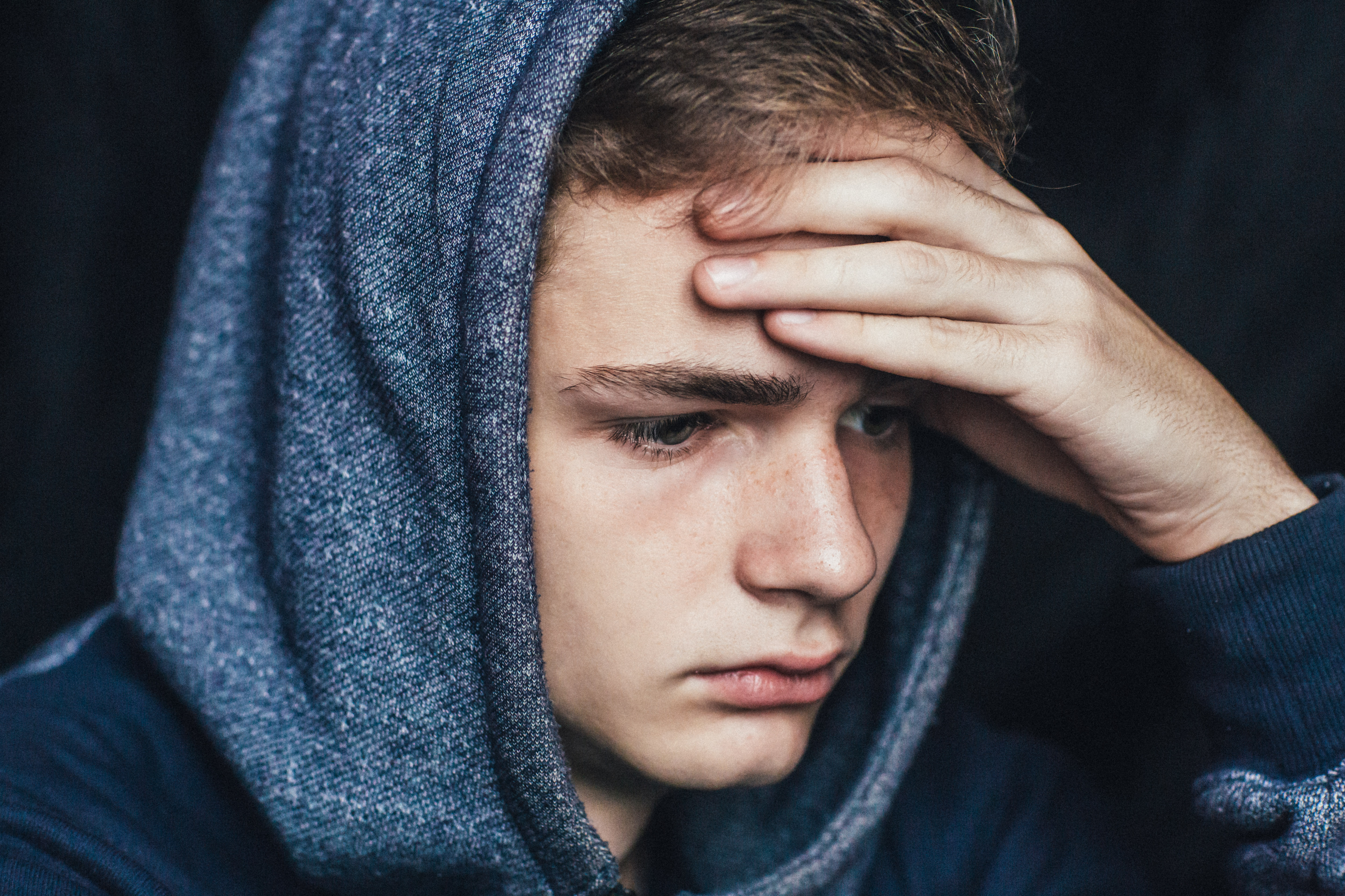 A sad young man in a blue hoodie | Source: Shutterstock