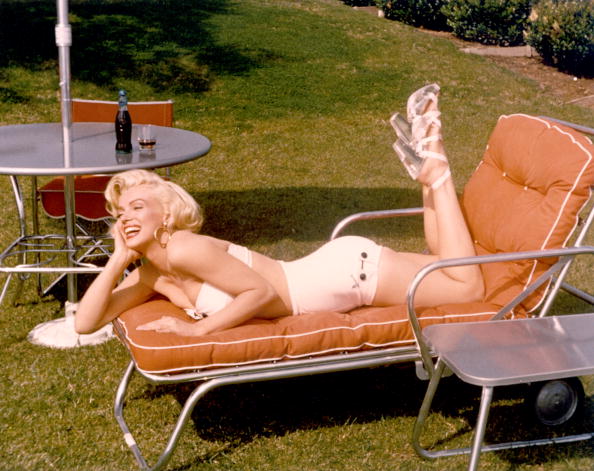  Actress Marilyn Monroe poses for a portrait in a bathing suit and high heels with a bottle of Coca-Cola in a glass on a table behind her | Photo: Getty Images