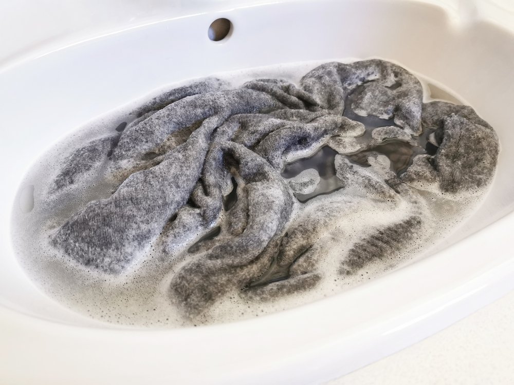 Man washing his few clothing in the sink | Photo: Shutterstock